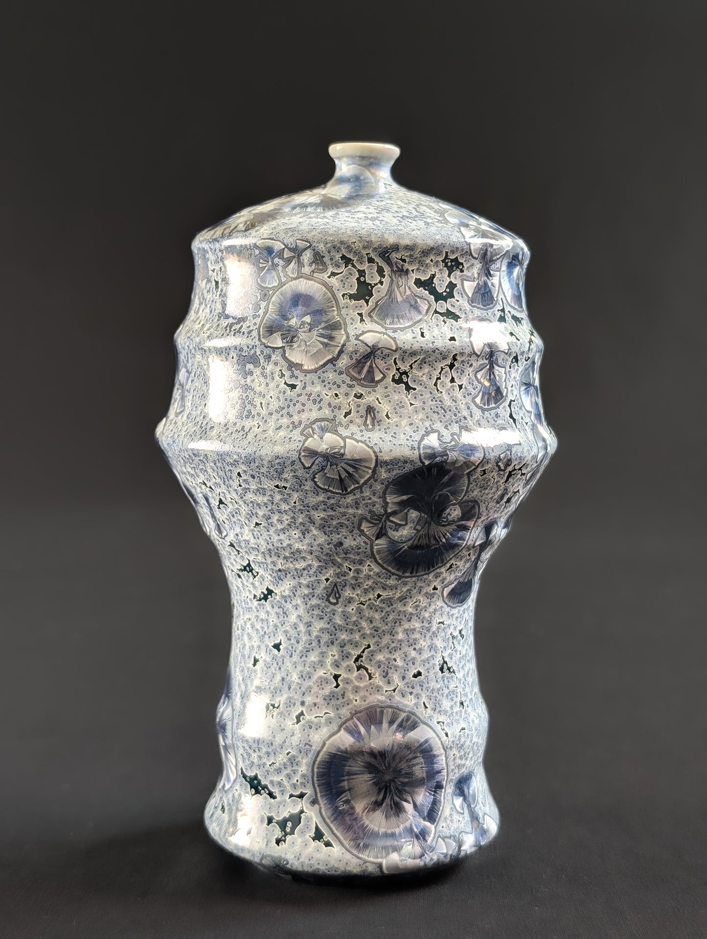 Ceramic vase with small and large crystals on a dark background