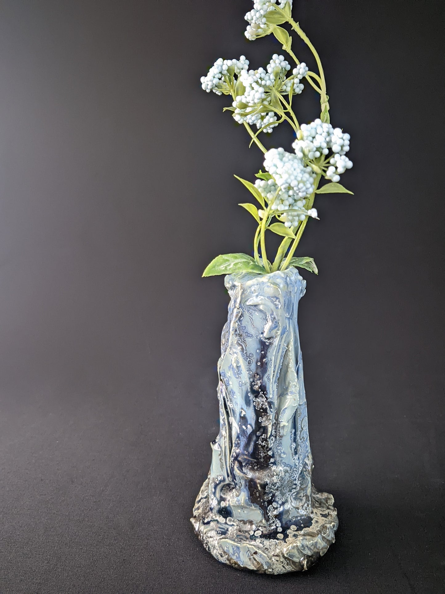 Elegant Ice Bound Single Flower Vase with cool, frosty blue and white tones, showcasing a smooth, glossy surface and an organic, tapered shape, set against a dark backdrop.