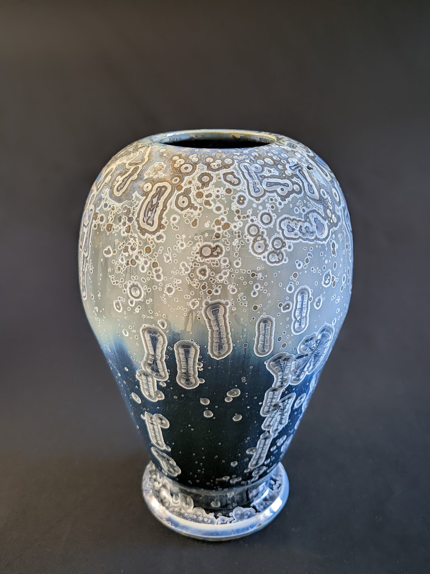 A sculptural ceramic vase with deep blue and gray crystalline formations, blending ancient elegance with a futuristic aesthetic.