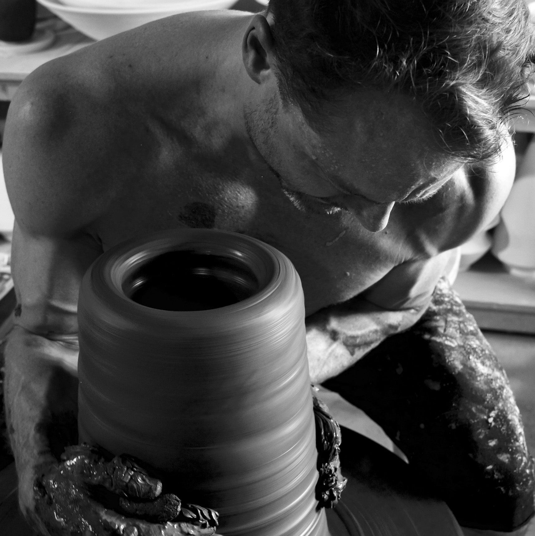 Close-up of Robbin Harris working on a tall ceramic piece, his fingers carefully refining the form on the spinning wheel. Captured in black and white by photographer David Marion.