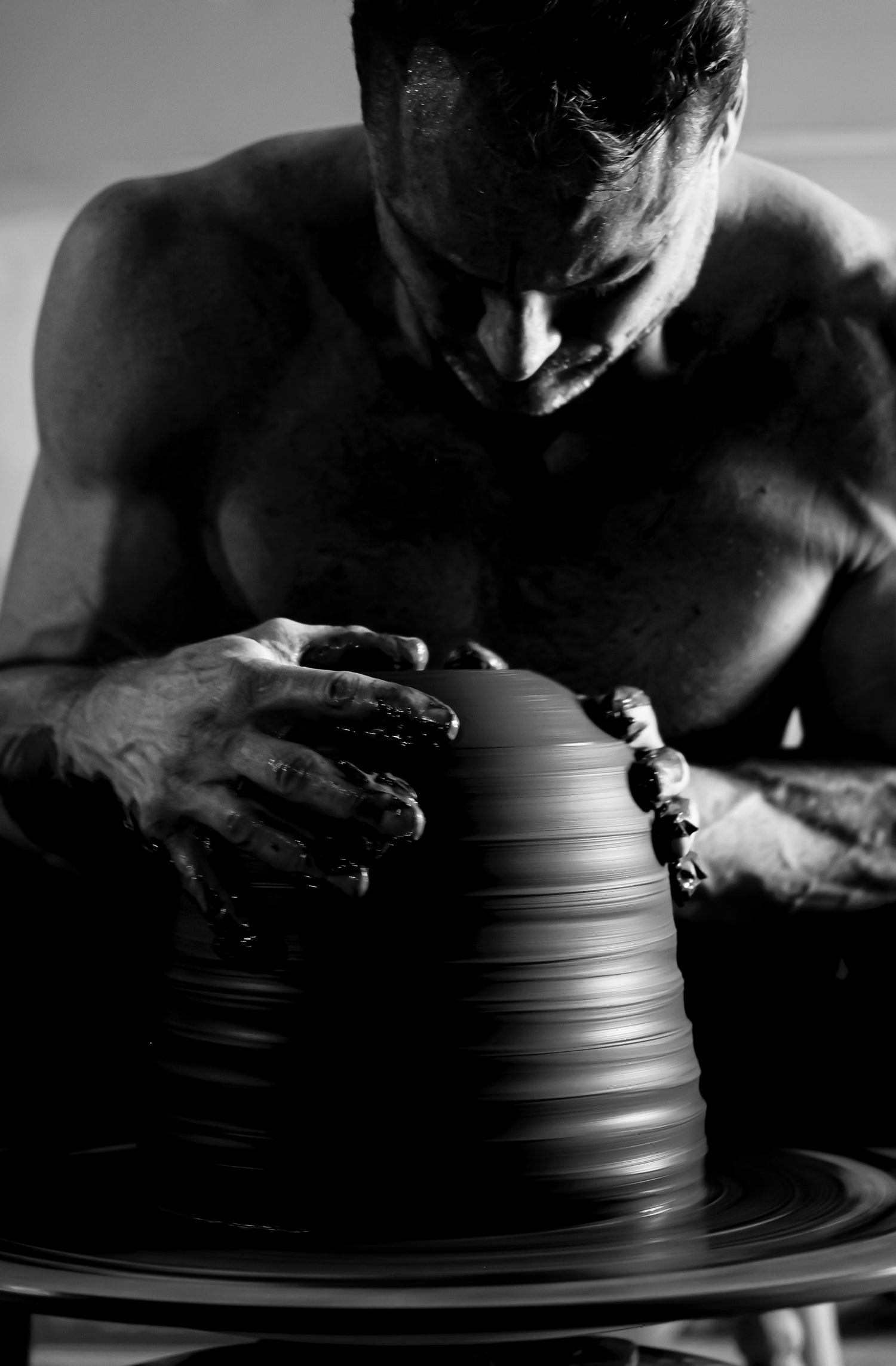 Close-up of Robbin Harris working on a tall ceramic piece, his fingers carefully refining the form on the spinning wheel. Captured in black and white by photographer David Marion.