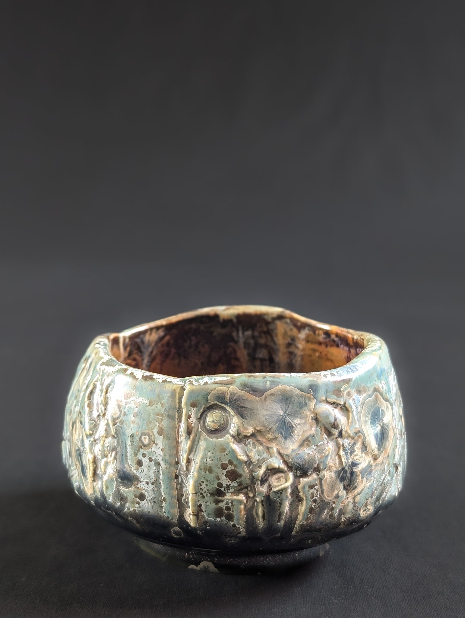Side view of 'Verdigris' chawan by Robbin Harris, showing matte green glaze with flowing vertical texture and silvery highlights.