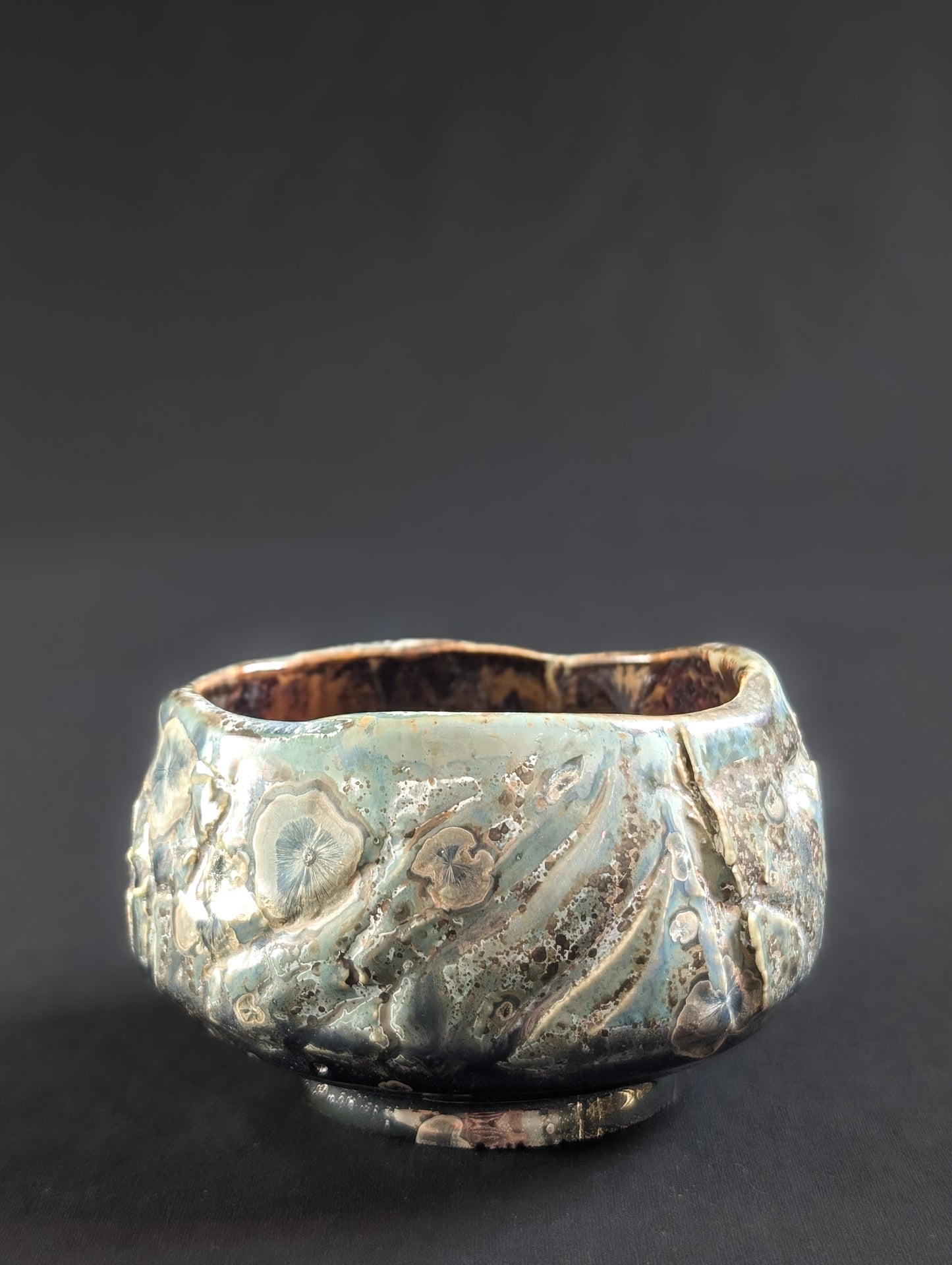 Angled profile of 'Verdigris Drift', featuring soft green tones, metallic patches, and a subtly uneven rim.