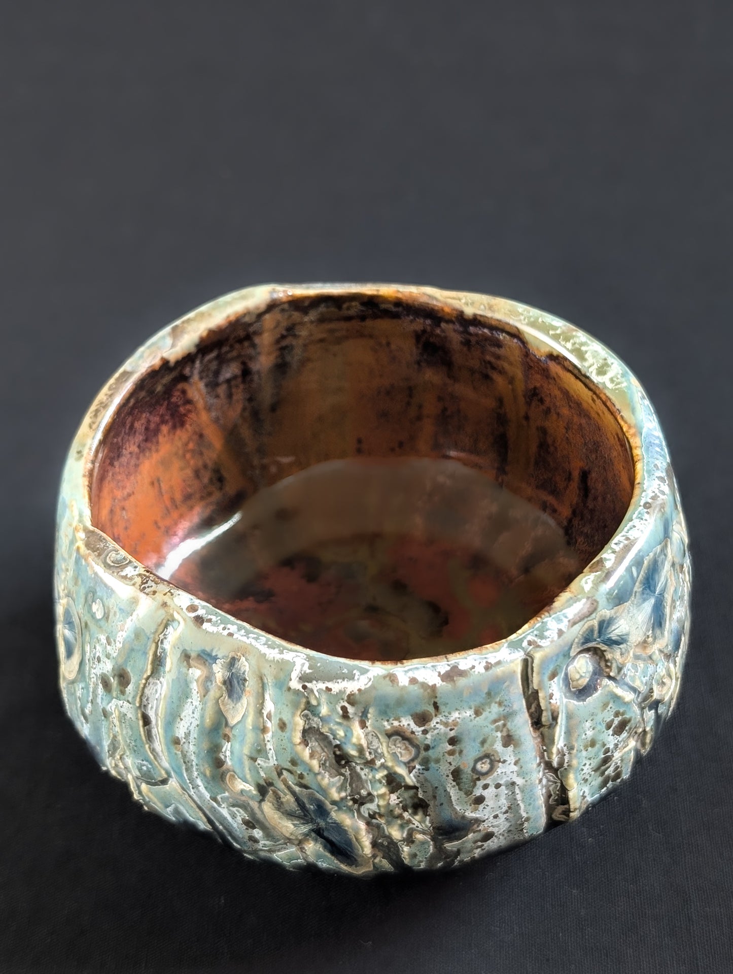 Top view of 'Verdigris', showing the irregular rim and warm brown interior glaze.