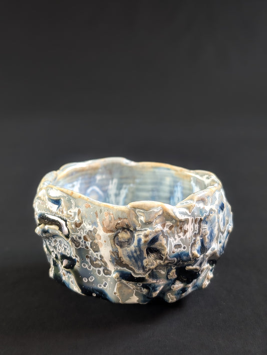 Side view of 'Yukihana' chawan by Robbin Harris, showing a deeply textured surface glazed in navy and dusty baby blue.