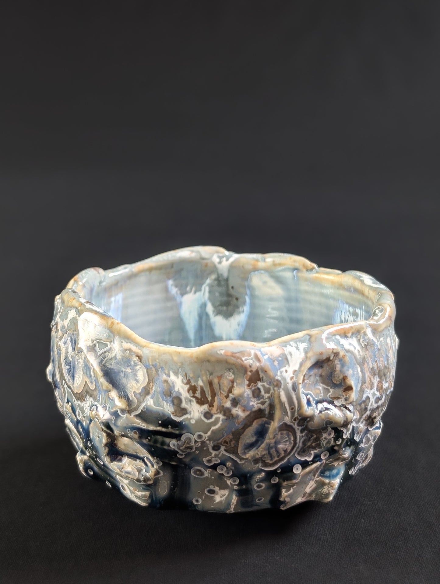 Textured crystalline porcelain tea bowl on a black background