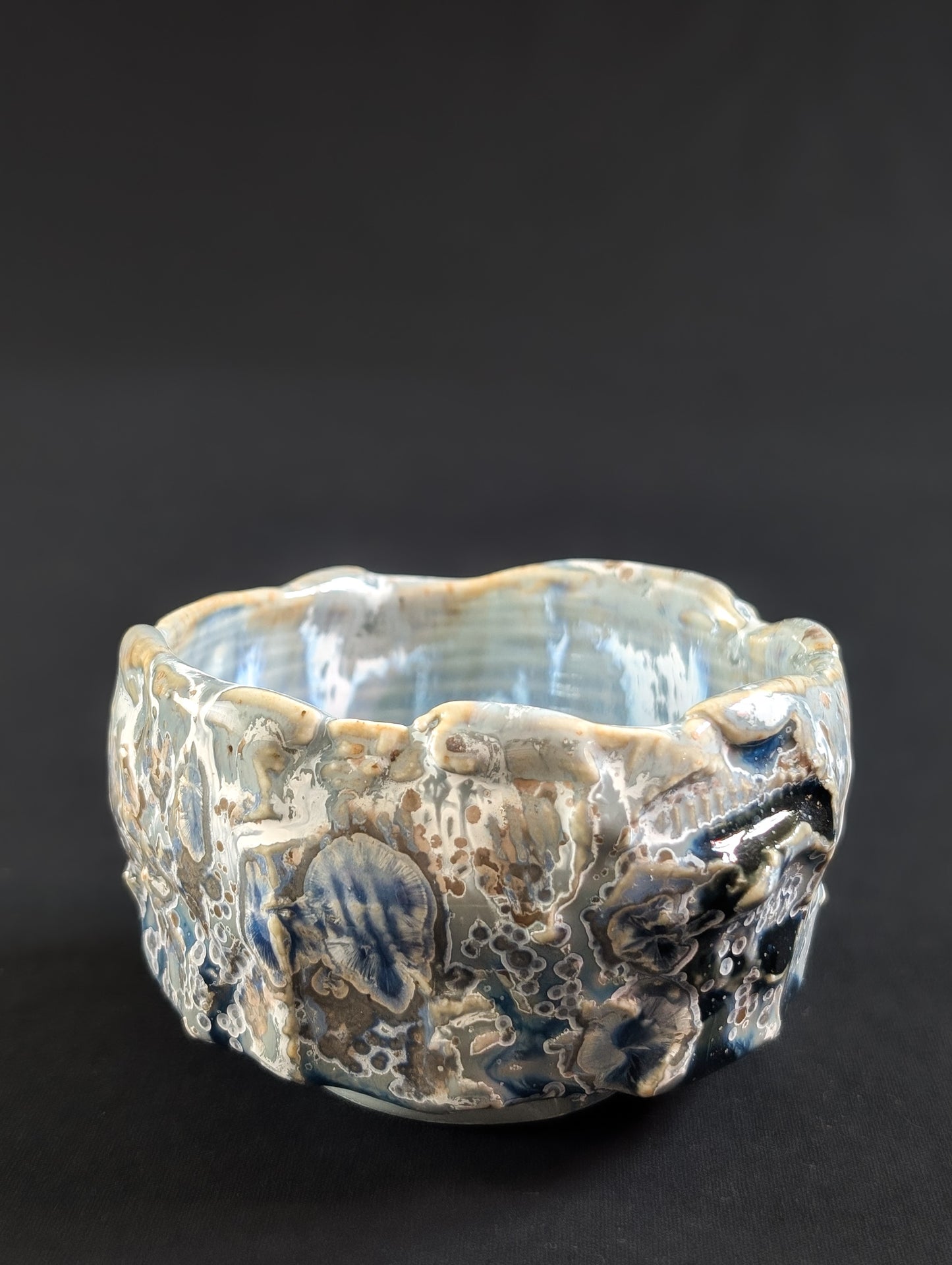 Ceramic tea bowl with textured surface on a dark background
