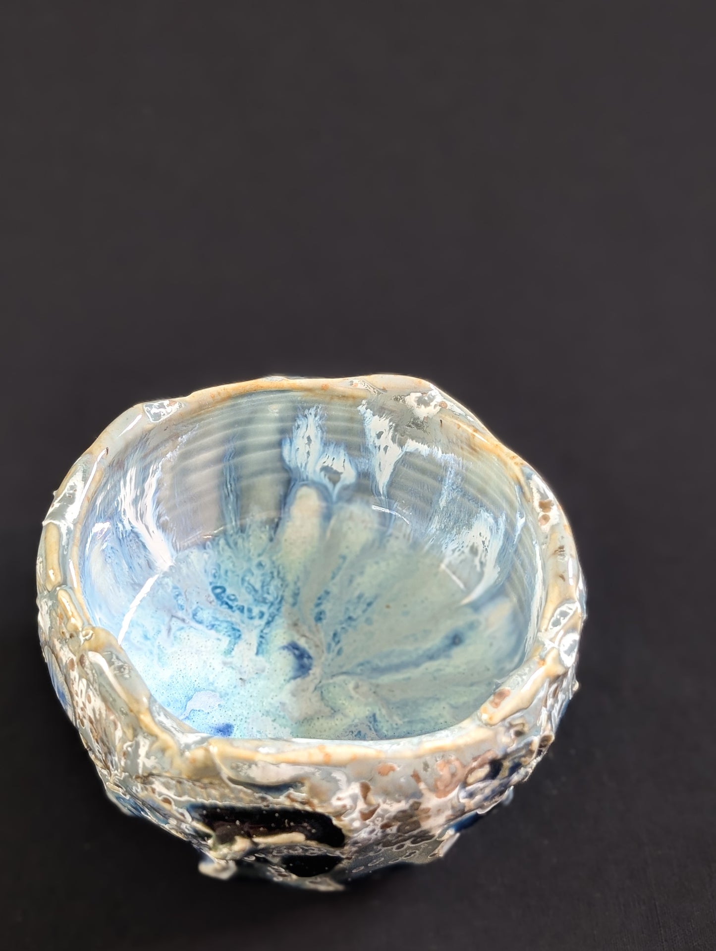 Top view of 'Yukihana' chawan, revealing a light blue interior with delicate glaze drips pooling at the bottom.

