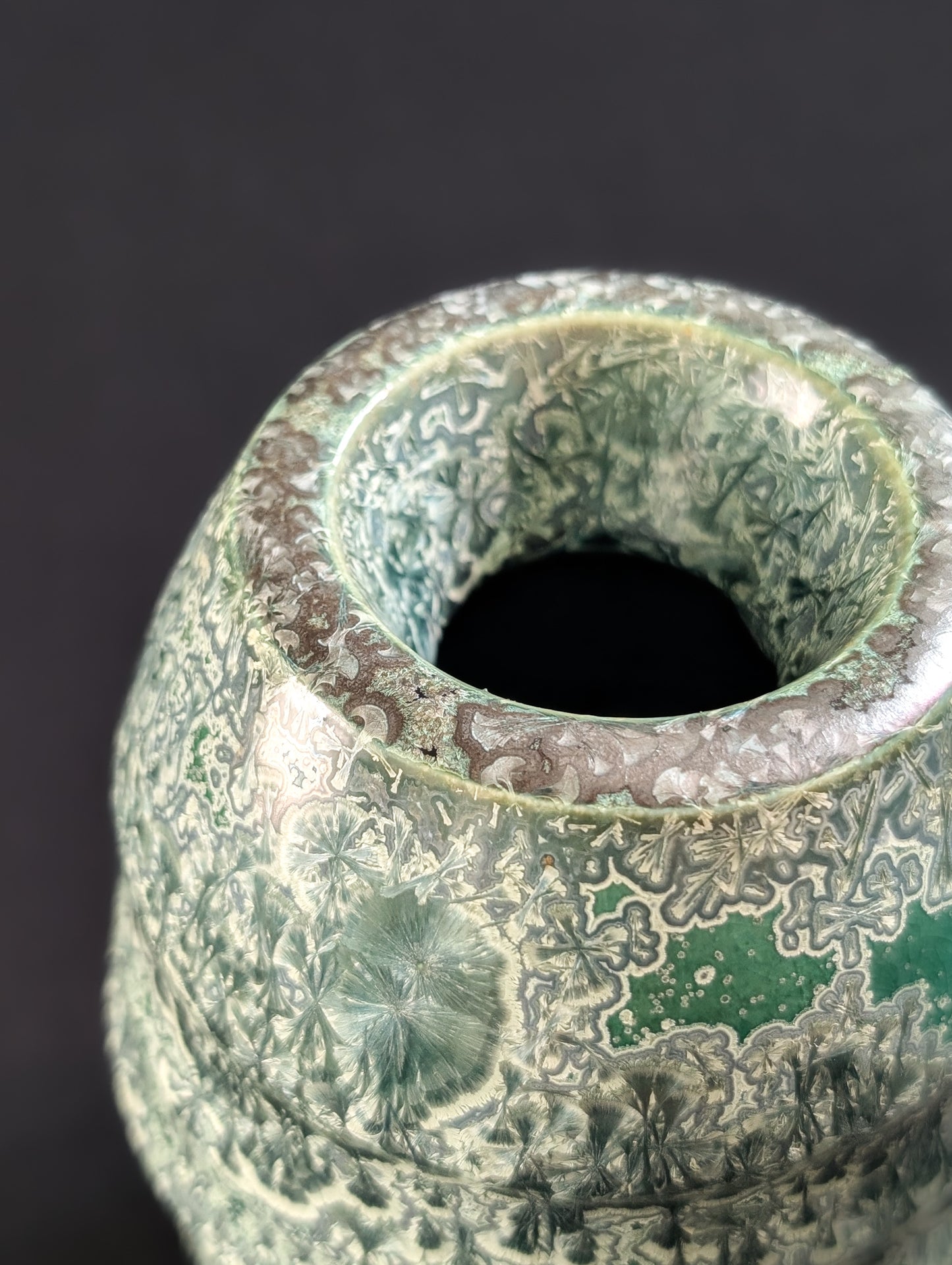 Detailed close-up of emerald crystalline vase with unique inward rim.