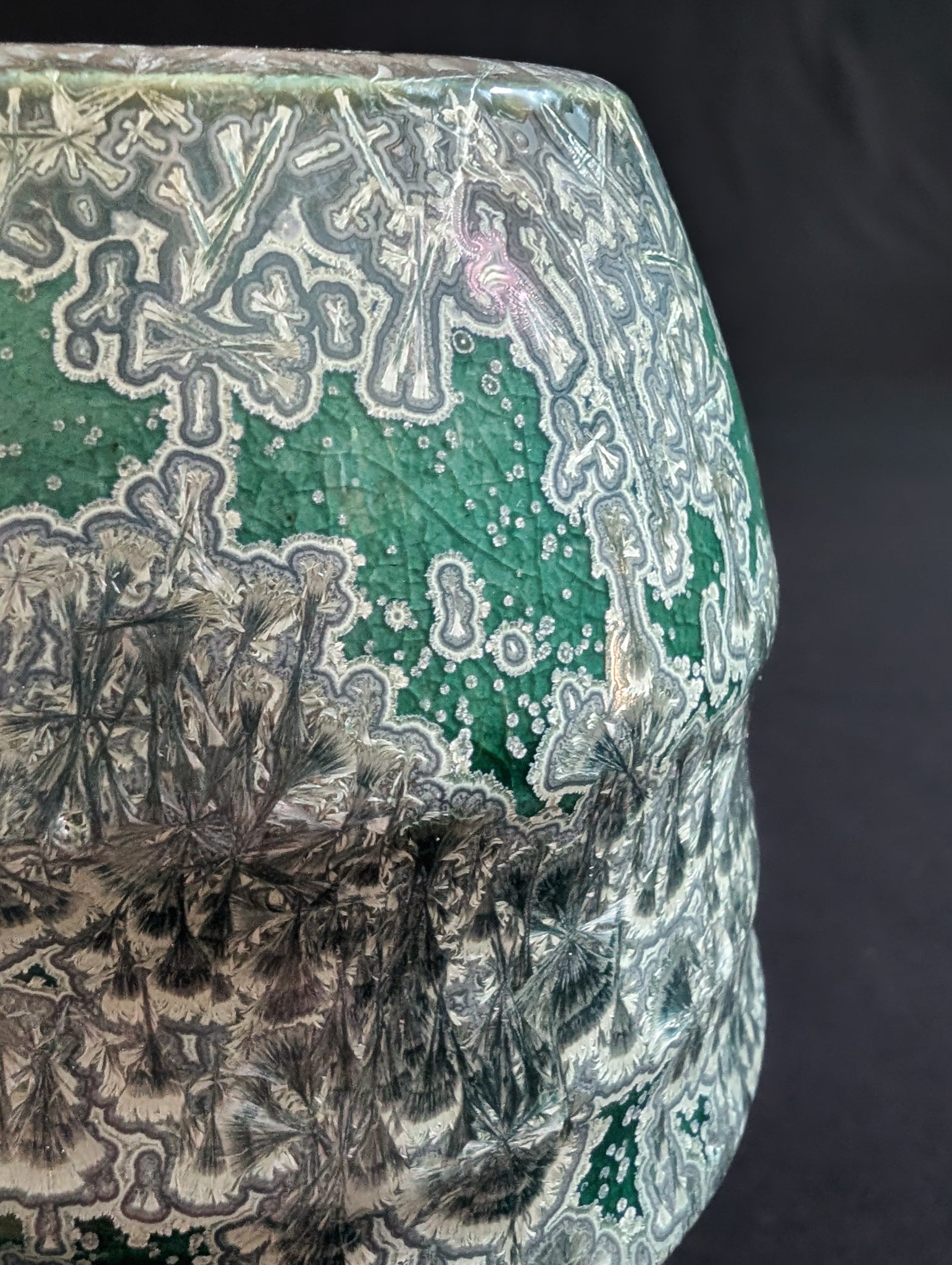 Upper section of emerald green crystalline vase by Robbin Harris, highlighting ribbed contours and detailed silver crystal patterns.