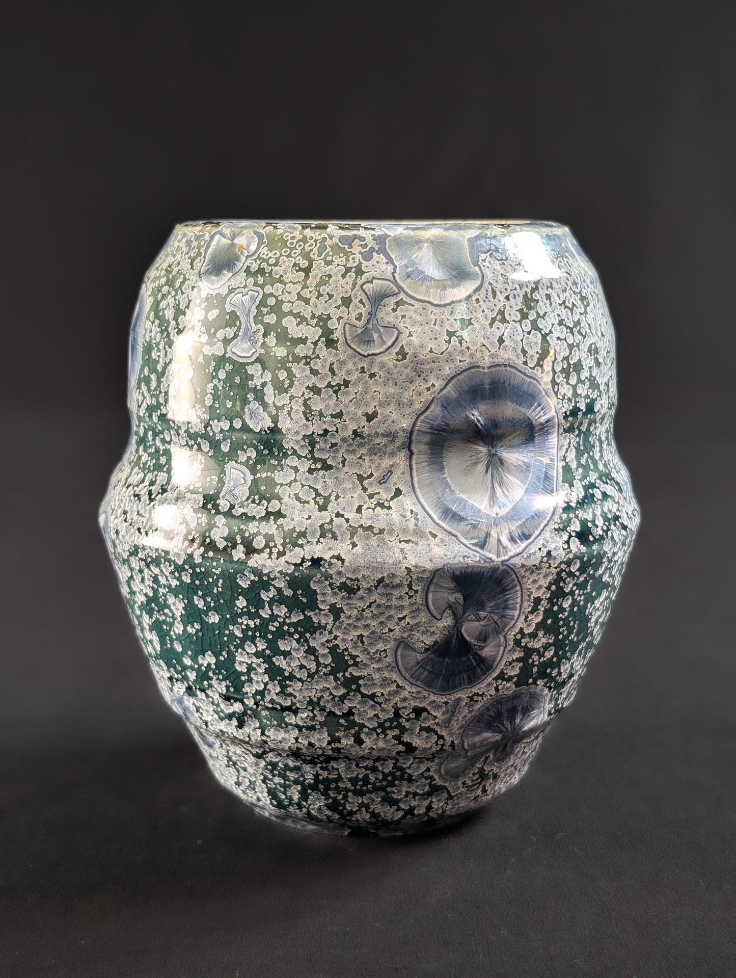 Decorative porcelain vase with crystallized surface on a dark background