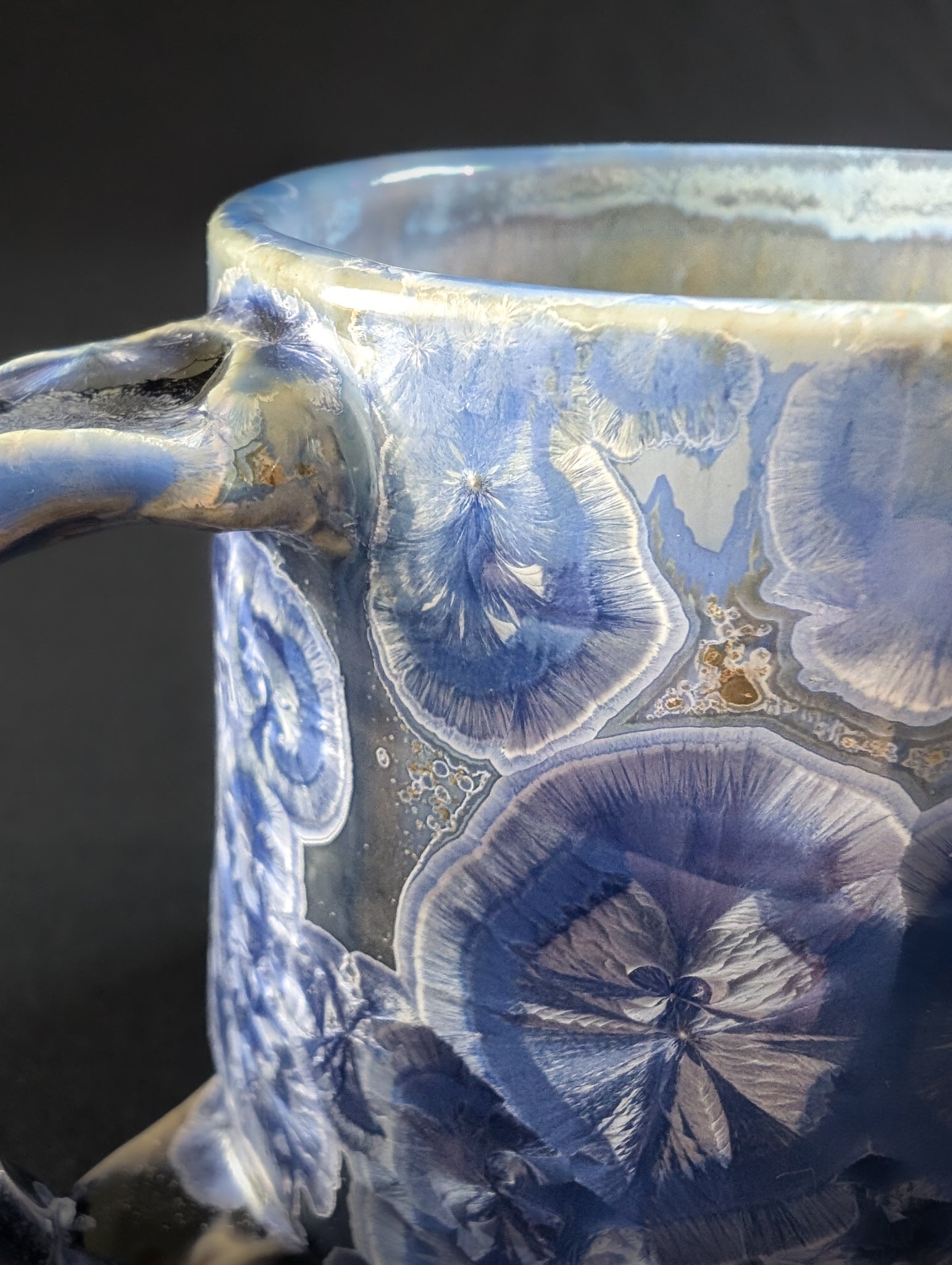 Ceramic mug with blue crystalline pattern on a dark background