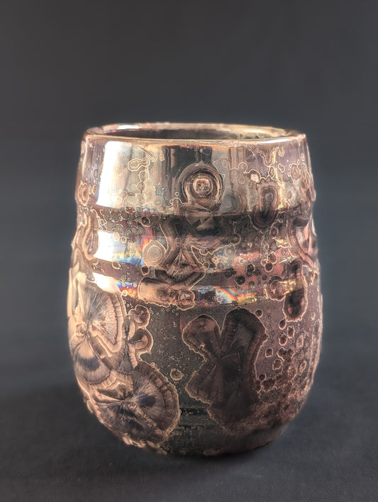 'Ember' mug with warm red glaze and deep brown crystals on a glossy surface.