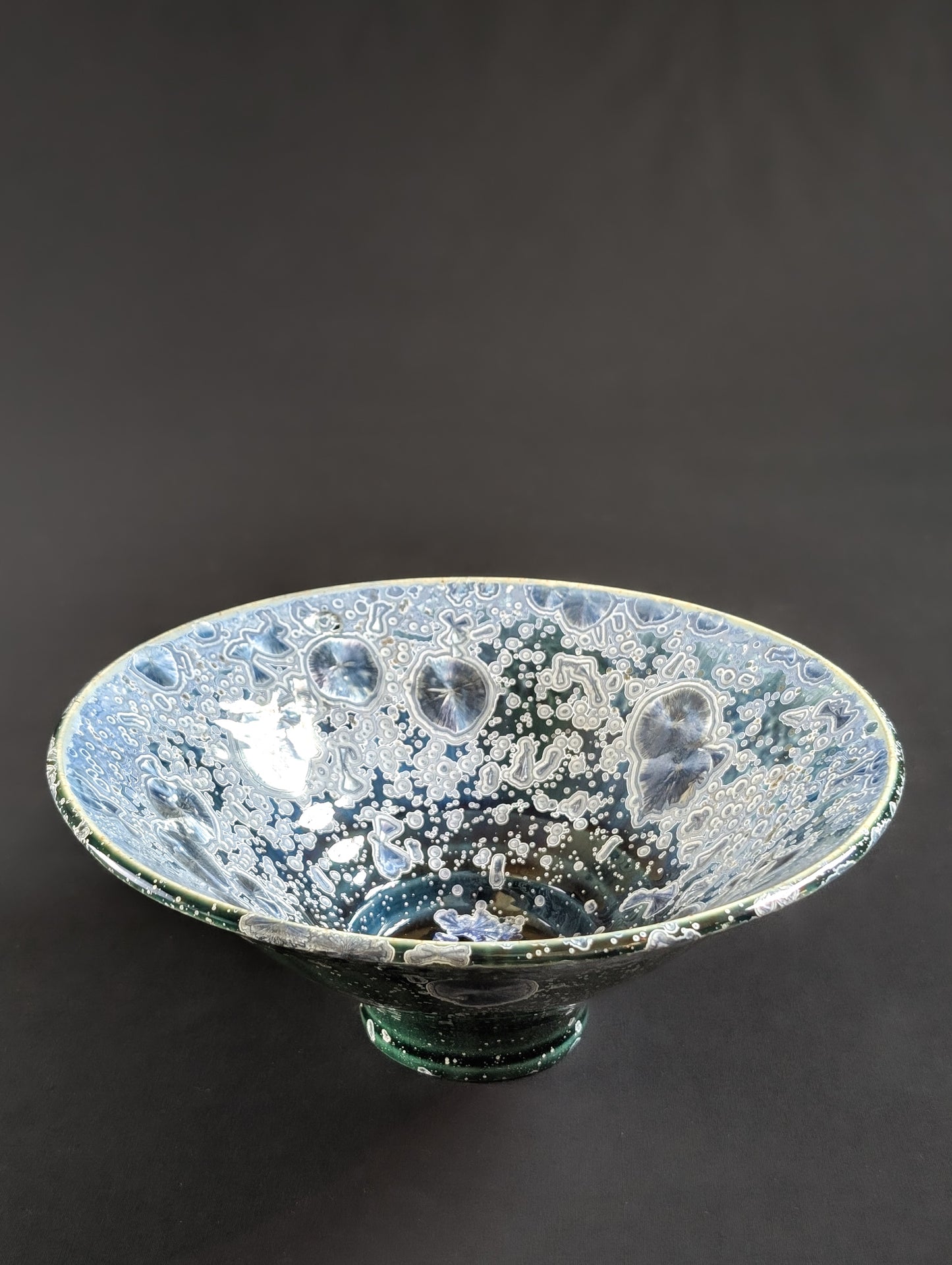 Porcelain treasure dish by ceramic artist Robbin Harris against a black background.