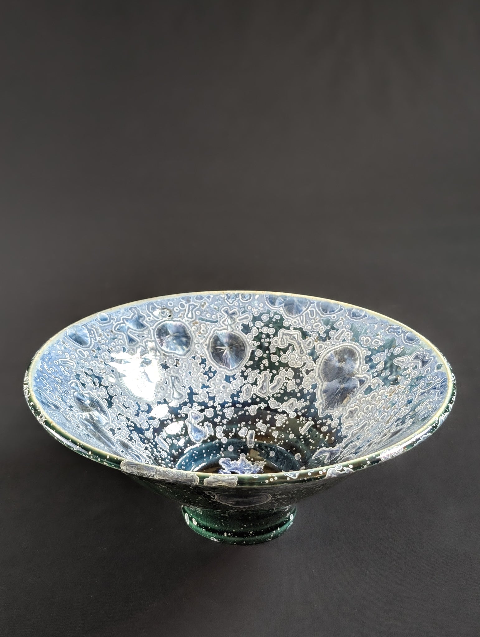 Porcelain treasure dish by ceramic artist Robbin Harris against a black background.