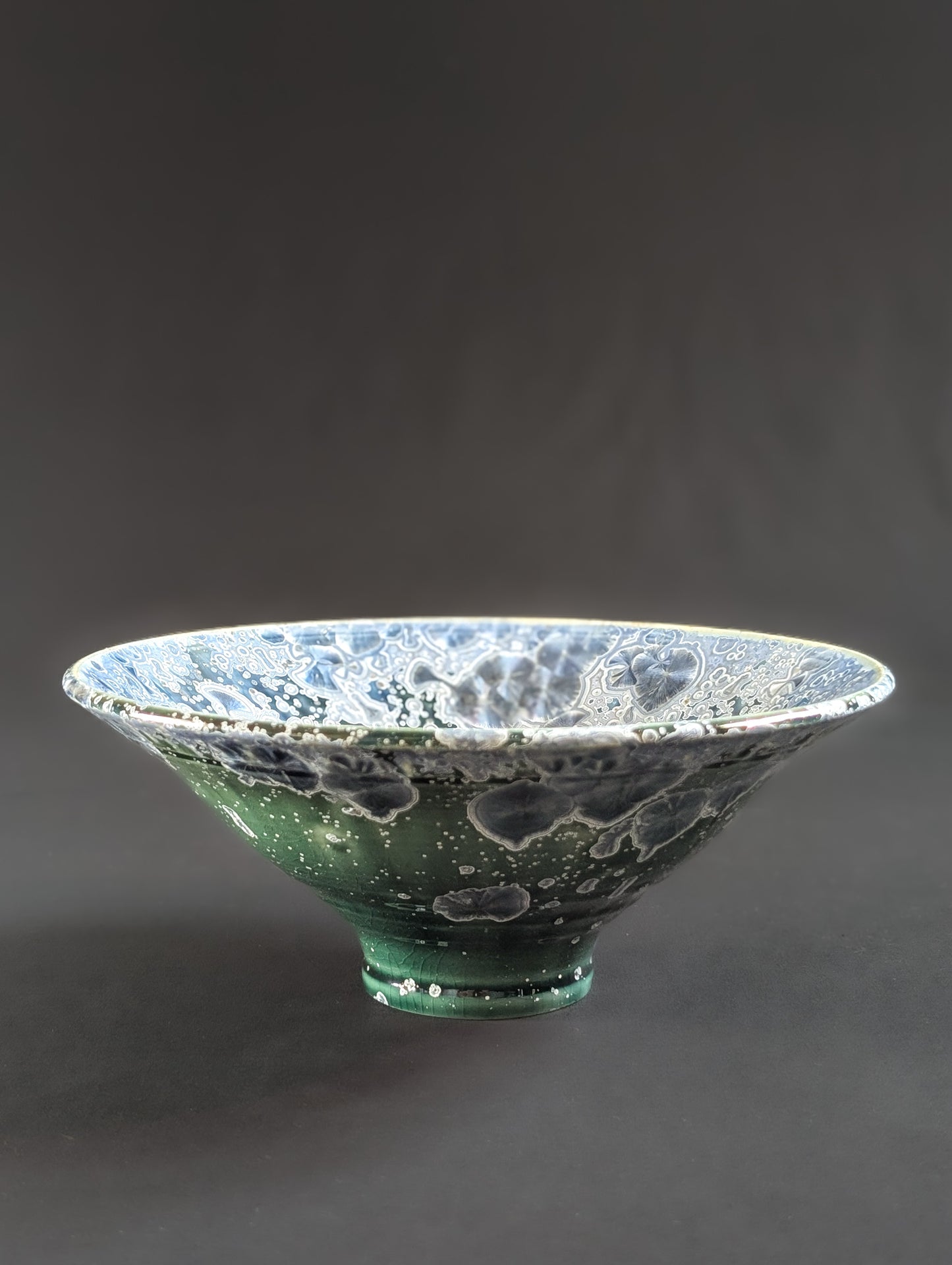 Crystalline ceramic ring dish showcasing sapphire blue crystals against an emerald green background.