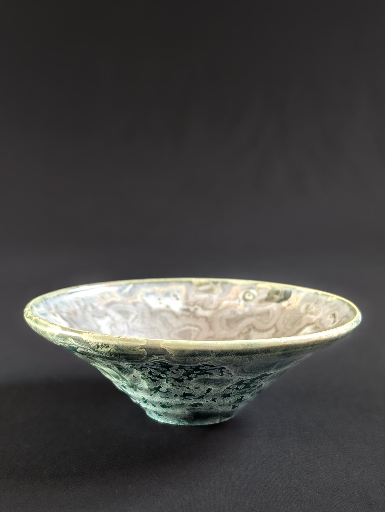 Crystalline porcelain ring dish with vibrant green outside and metal colored inside.