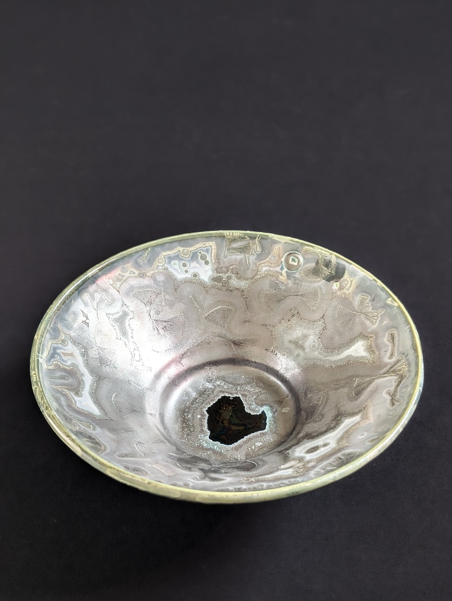 Crystalline glazed trinket dish by ceramic artist Robbin Harris against a black background.