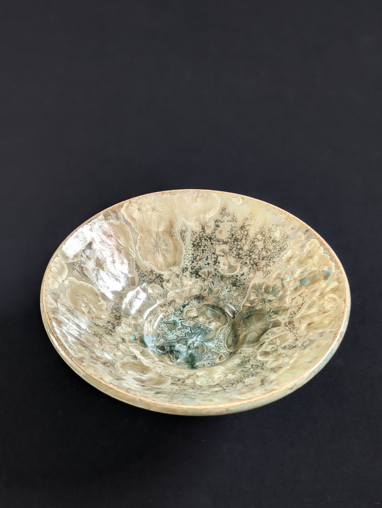 Top view of a beautiful yellow and green porcelain trinket dish by Robbin Harris against a black background.