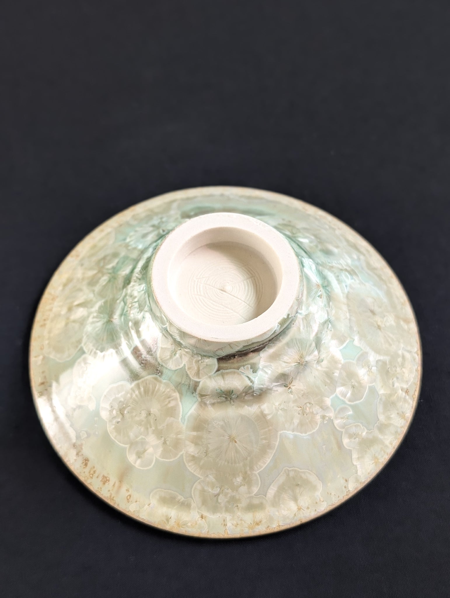 Bottom view of porcelain spice dish with light beige crystals.