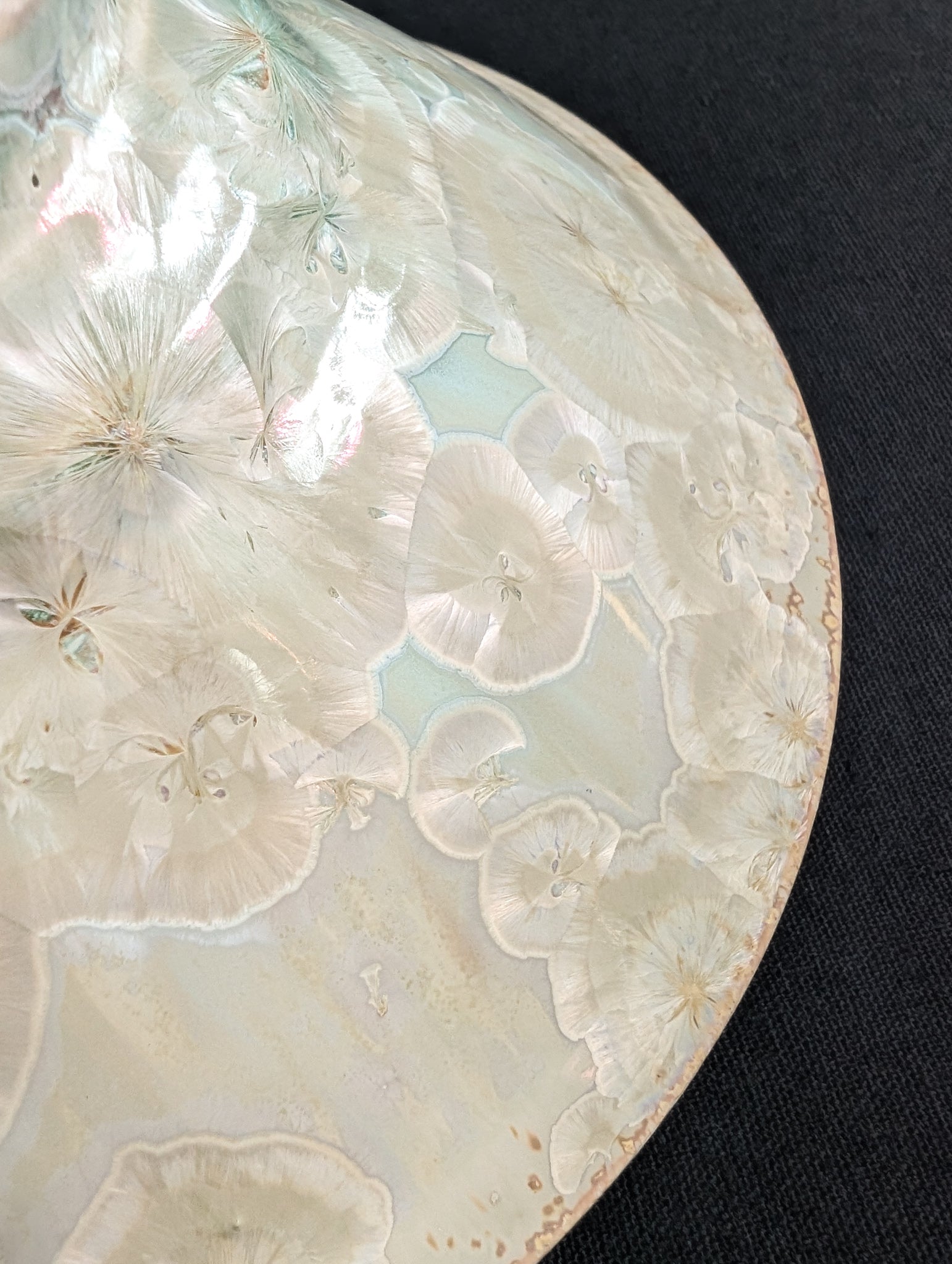 Close up of light cream crystals on the outside rim of crystalline ring dish by ceramic artist Robbin Harris.