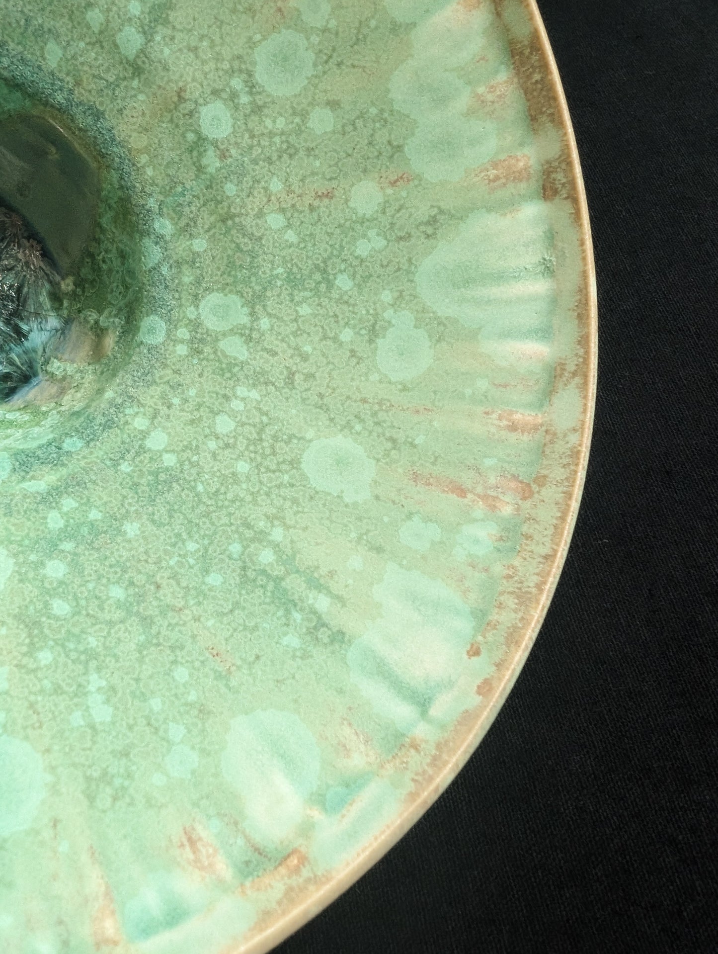 Close up view of inside rim of matte green ceramic dish by Robbin Harris.
