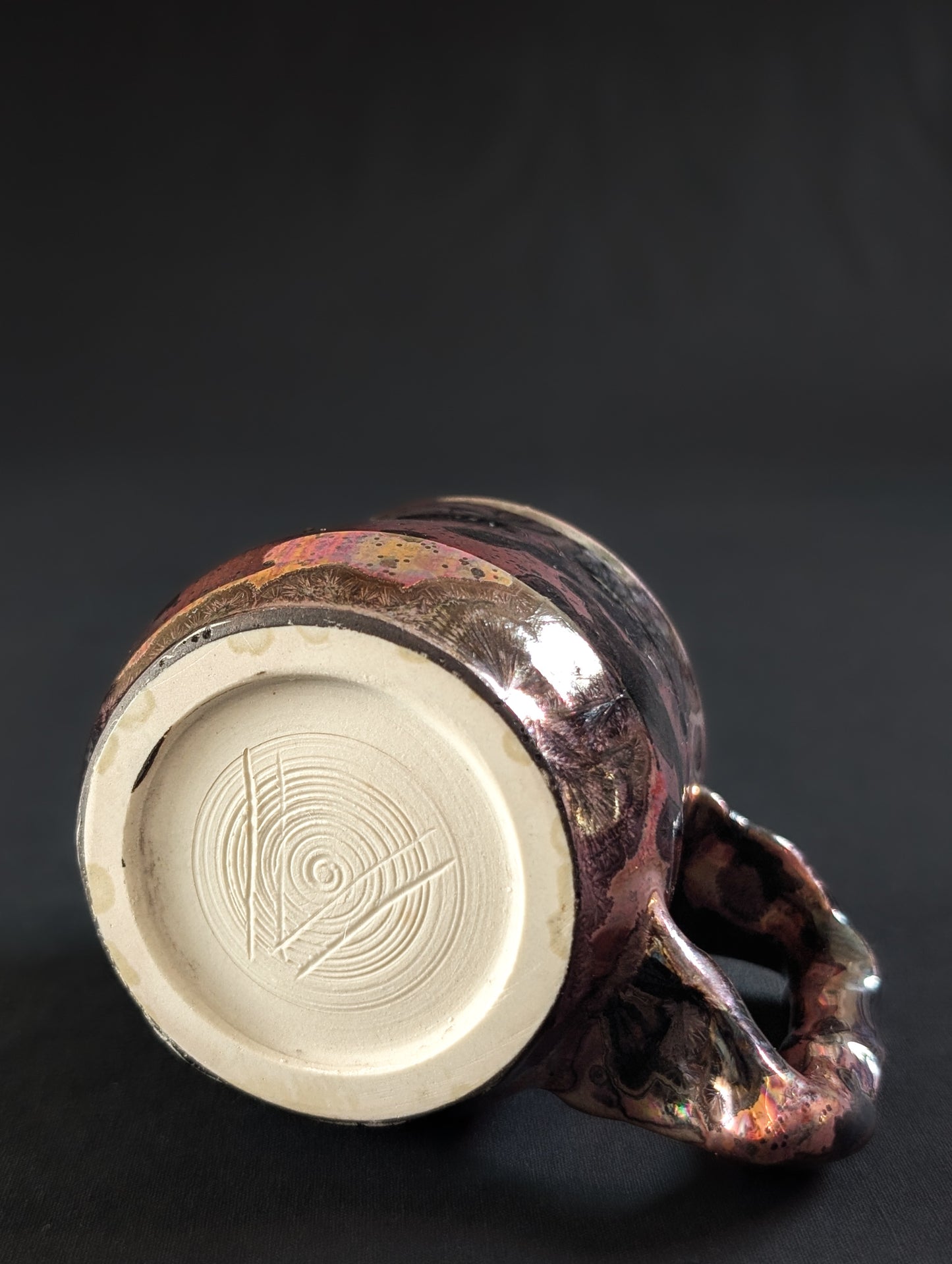 Underside of the Pink Nebula mug, showing the raw porcelain foot with Robbin’s carved “V” maker’s mark.