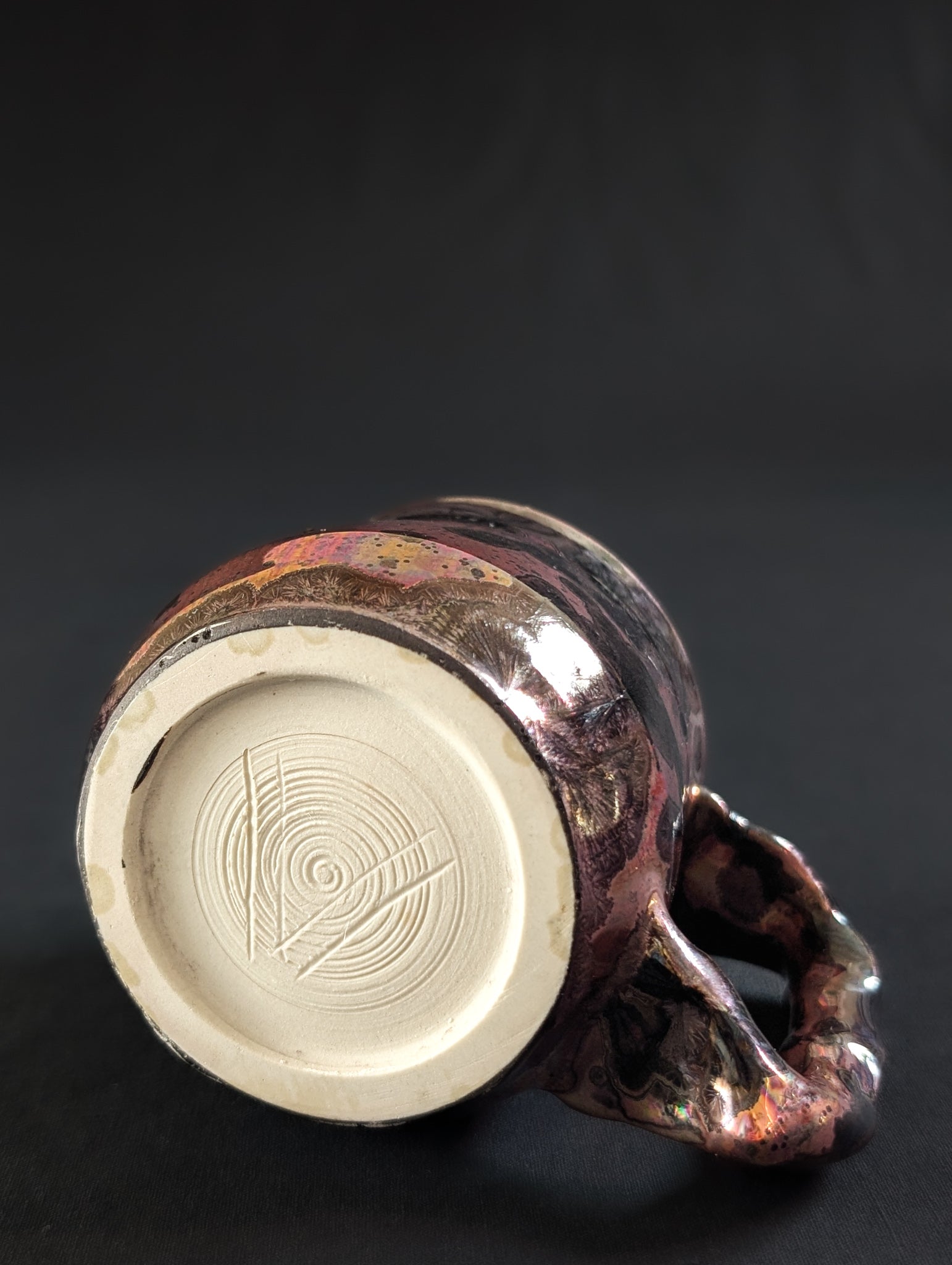 Underside of the Pink Nebula mug, showing the raw porcelain foot with Robbin’s carved “V” maker’s mark.