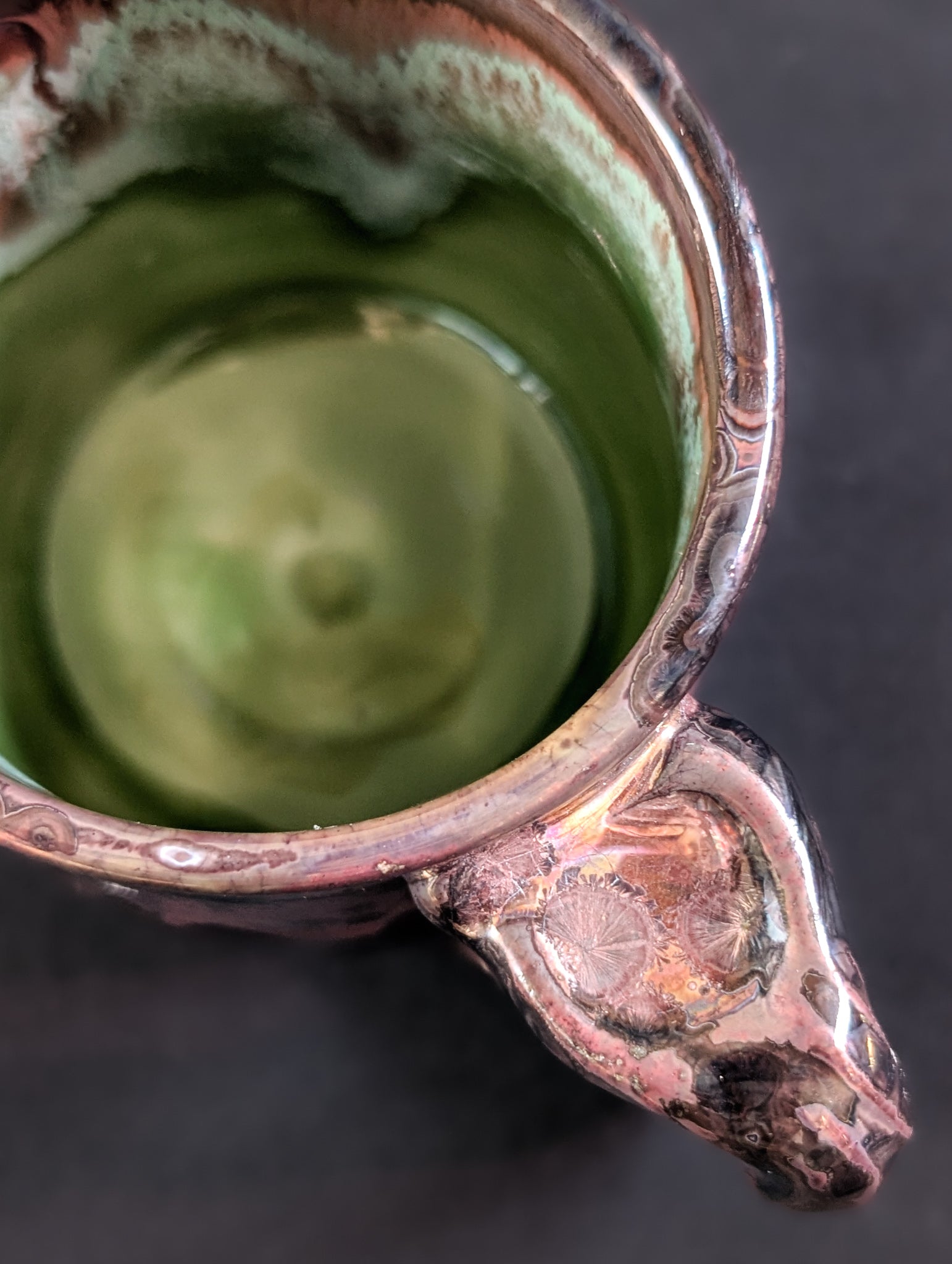Overhead view showing the celadon green interior and ergonomic handle of the Pink Nebula mug.
