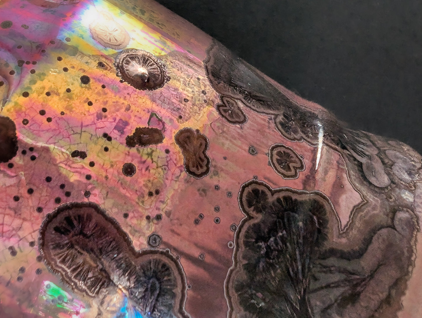 Detail of the crystalline glaze, highlighting the smoky black formations and iridescent pink hues that shift with the light.