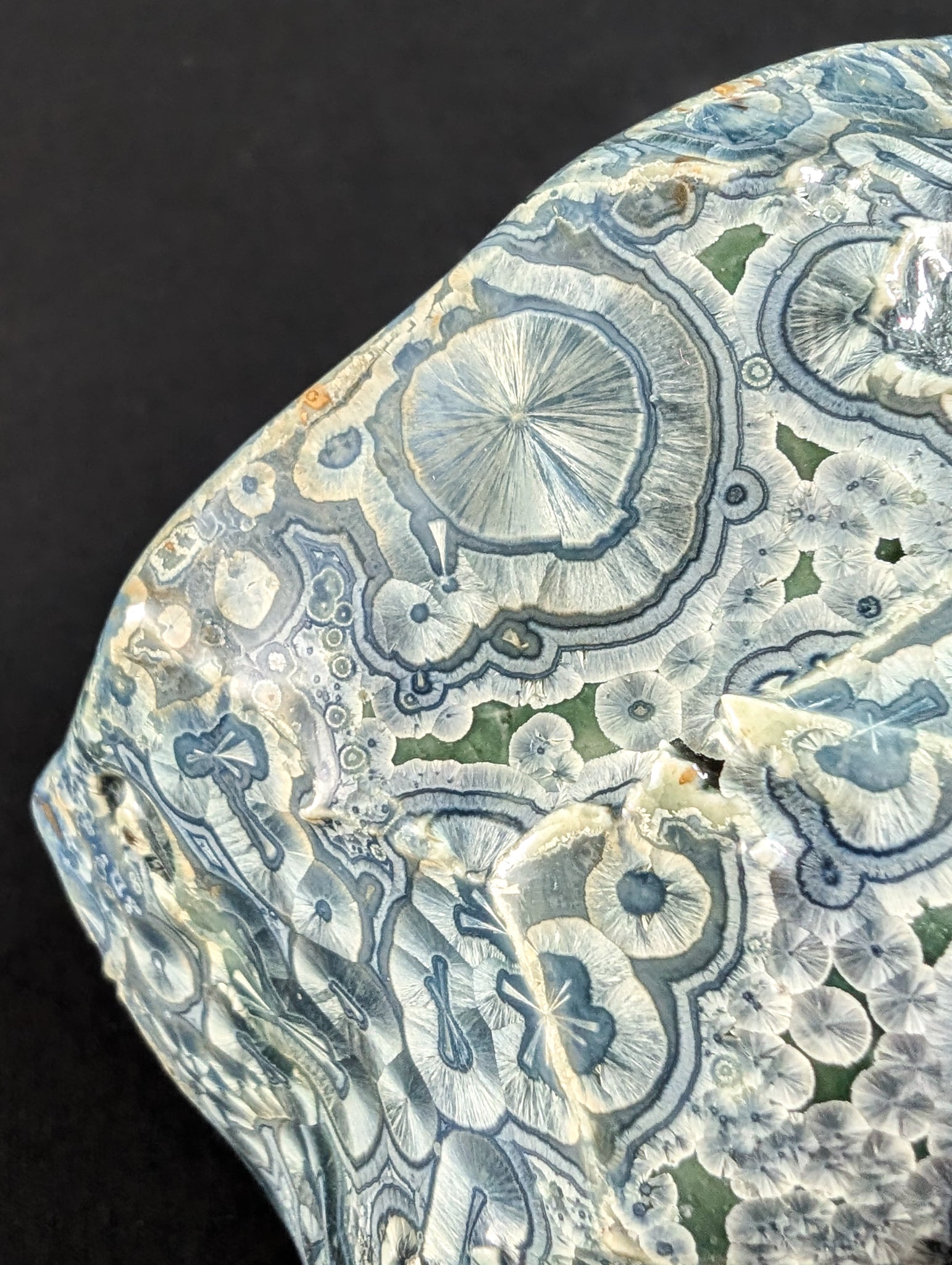 Close-up of 'Firevein' showing tiny blue crystals with wide white halos across a rough, carved surface.