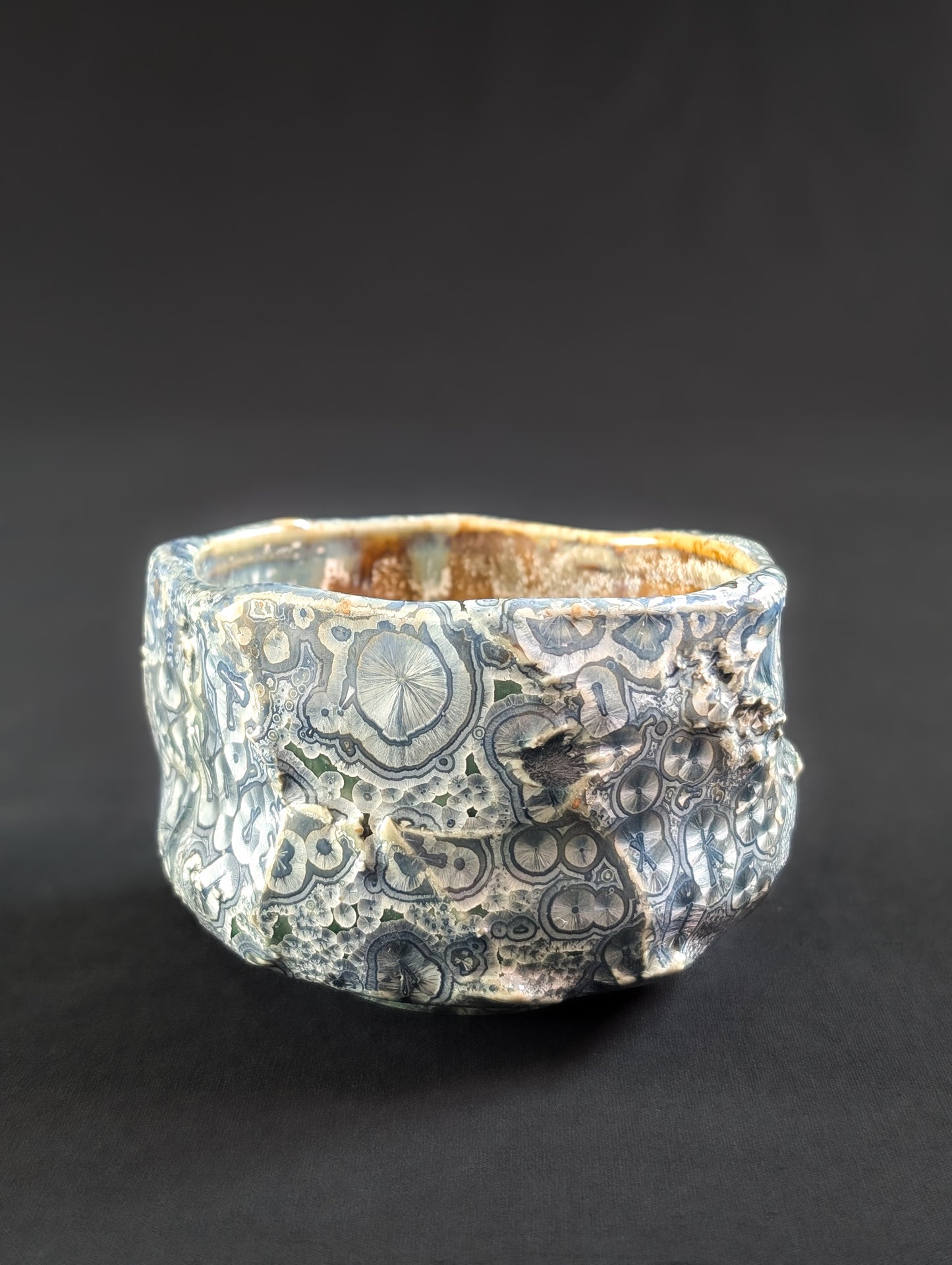 Angled profile of the chawan with jagged texture and dense crystalline surface resembling frosted stone.