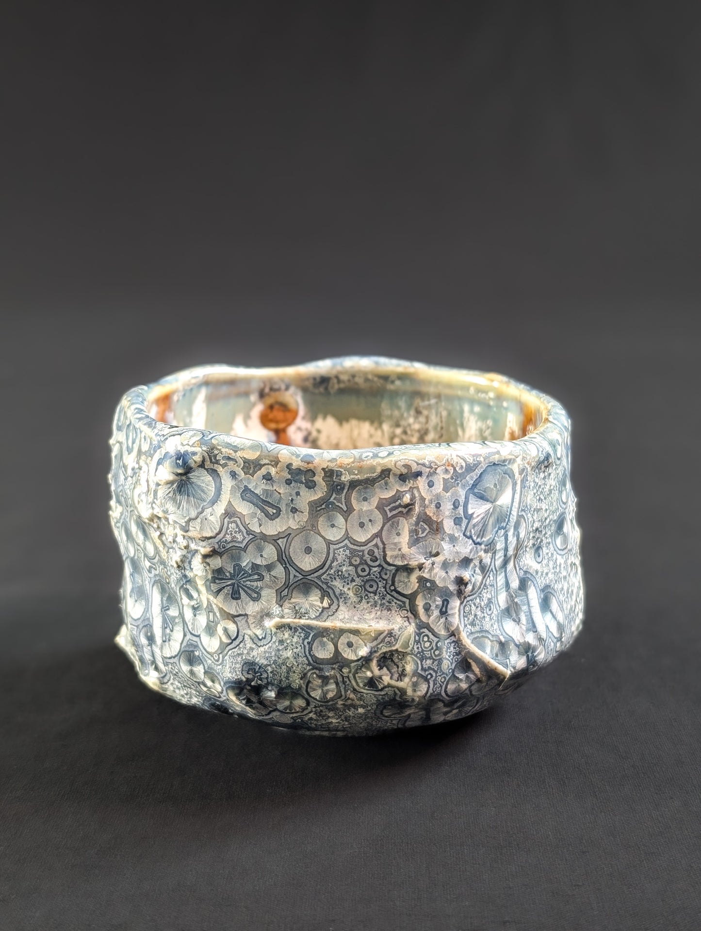 Side view of 'Firevein', where overcrystallized glaze blooms across a sharply faceted ceramic form.