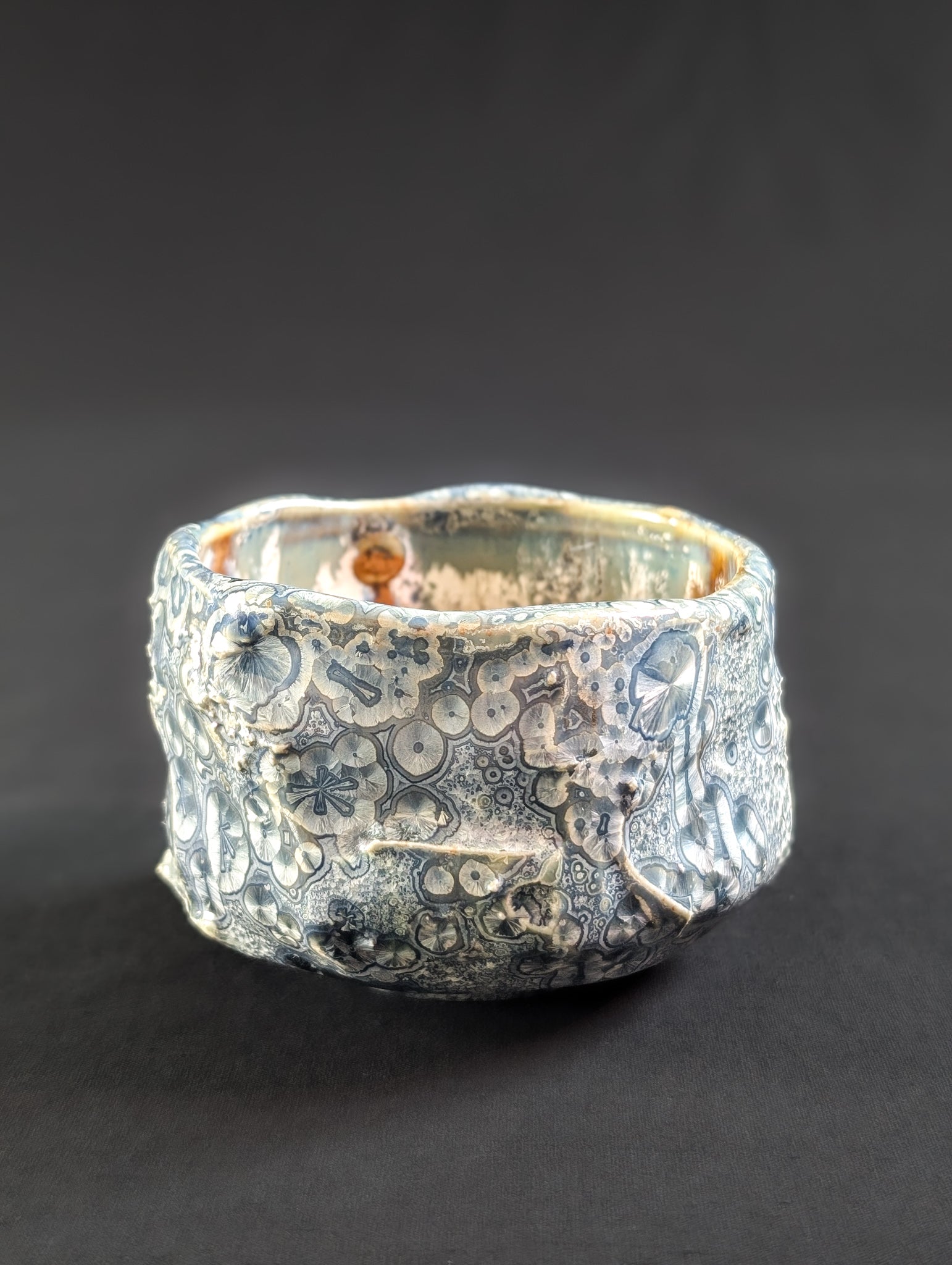 Side view of 'Firevein', where overcrystallized glaze blooms across a sharply faceted ceramic form.