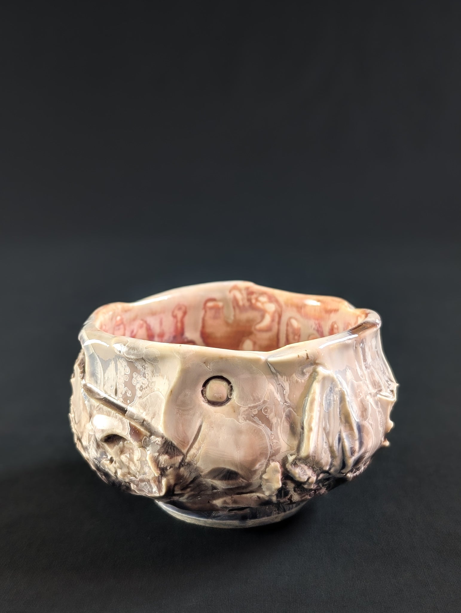 Side view of 'Cliff Rose' chawan by Robbin Harris, featuring a rock-carved texture with glossy soft pink glaze and deeper brown-gray tones in the carvings.