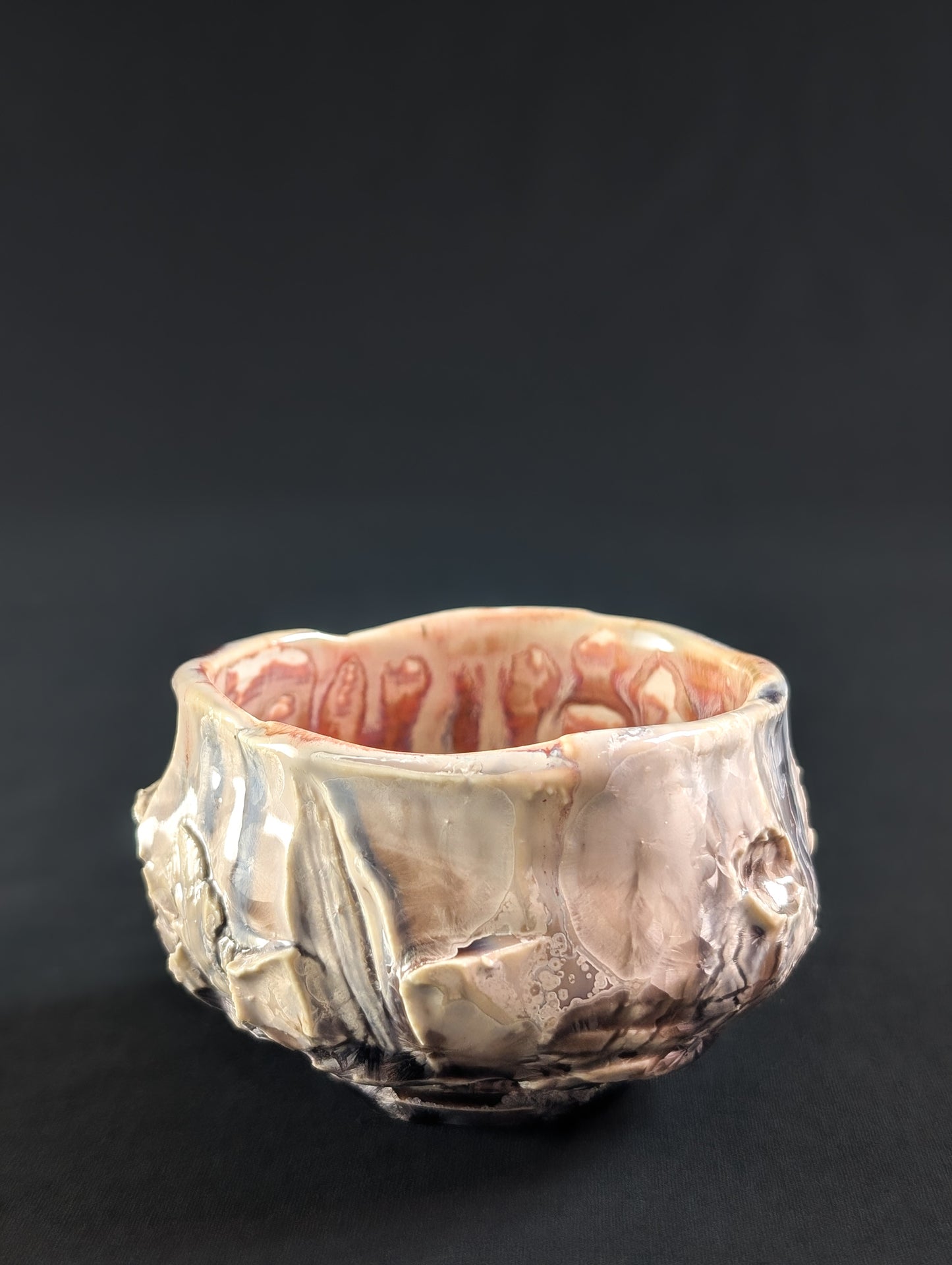 Side view showing carved stone texture beneath a soft pink glaze, with subtle crystal detail along the surface.