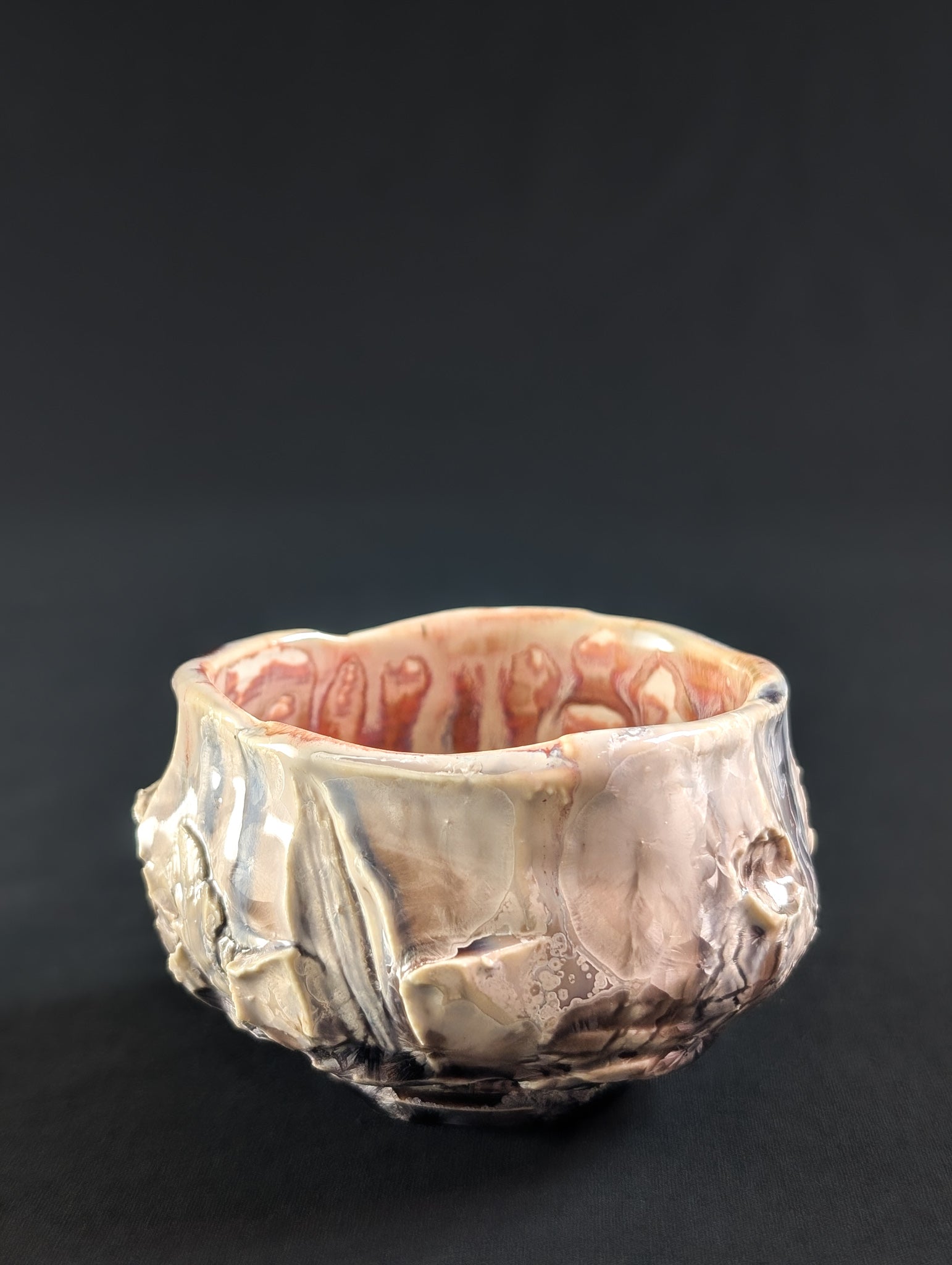 Side view showing carved stone texture beneath a soft pink glaze, with subtle crystal detail along the surface.