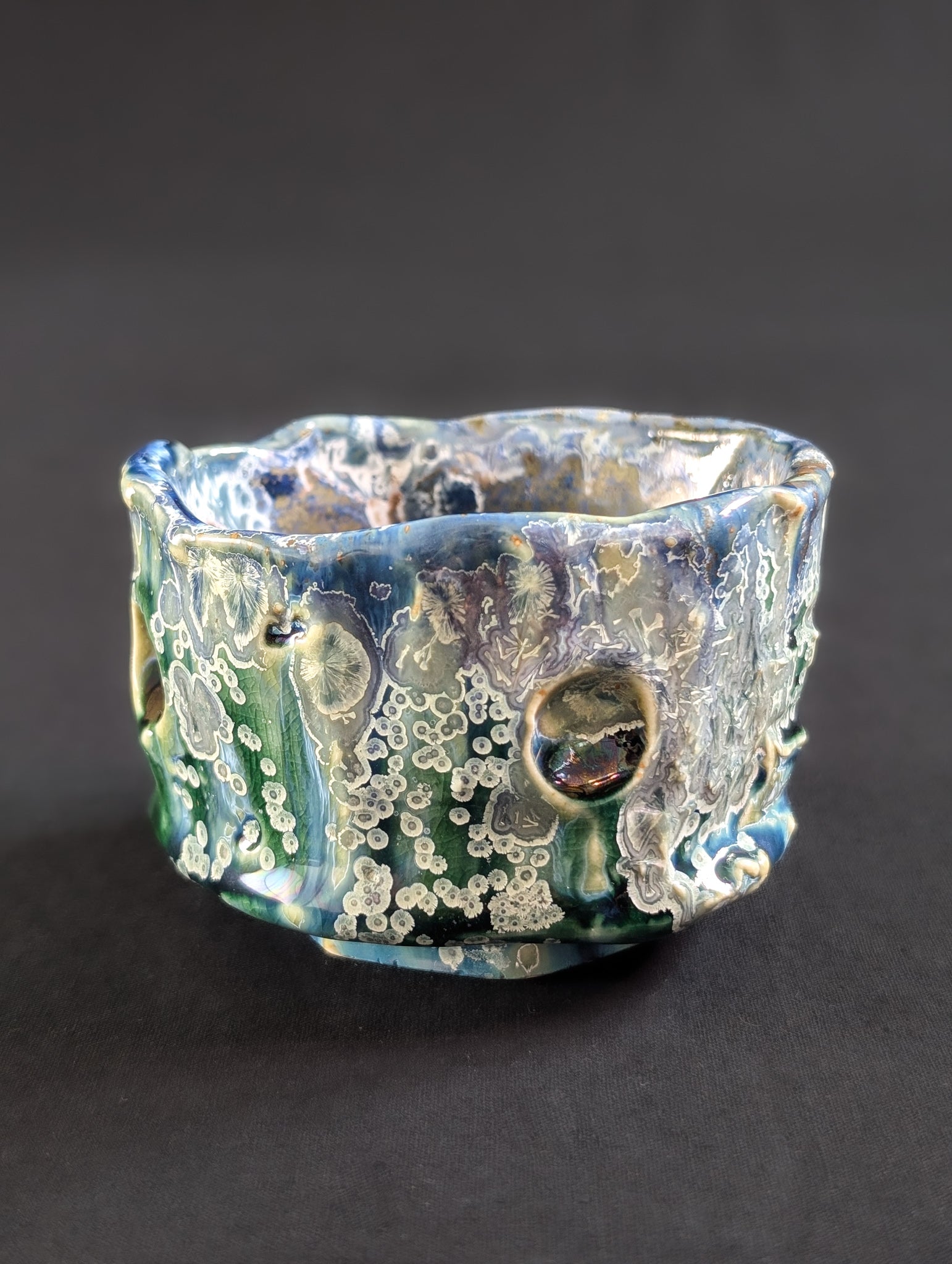 Profile of the 'Rainforest Whisper' tea bowl, highlighting its rainforest-inspired colors and dramatic surface texture.