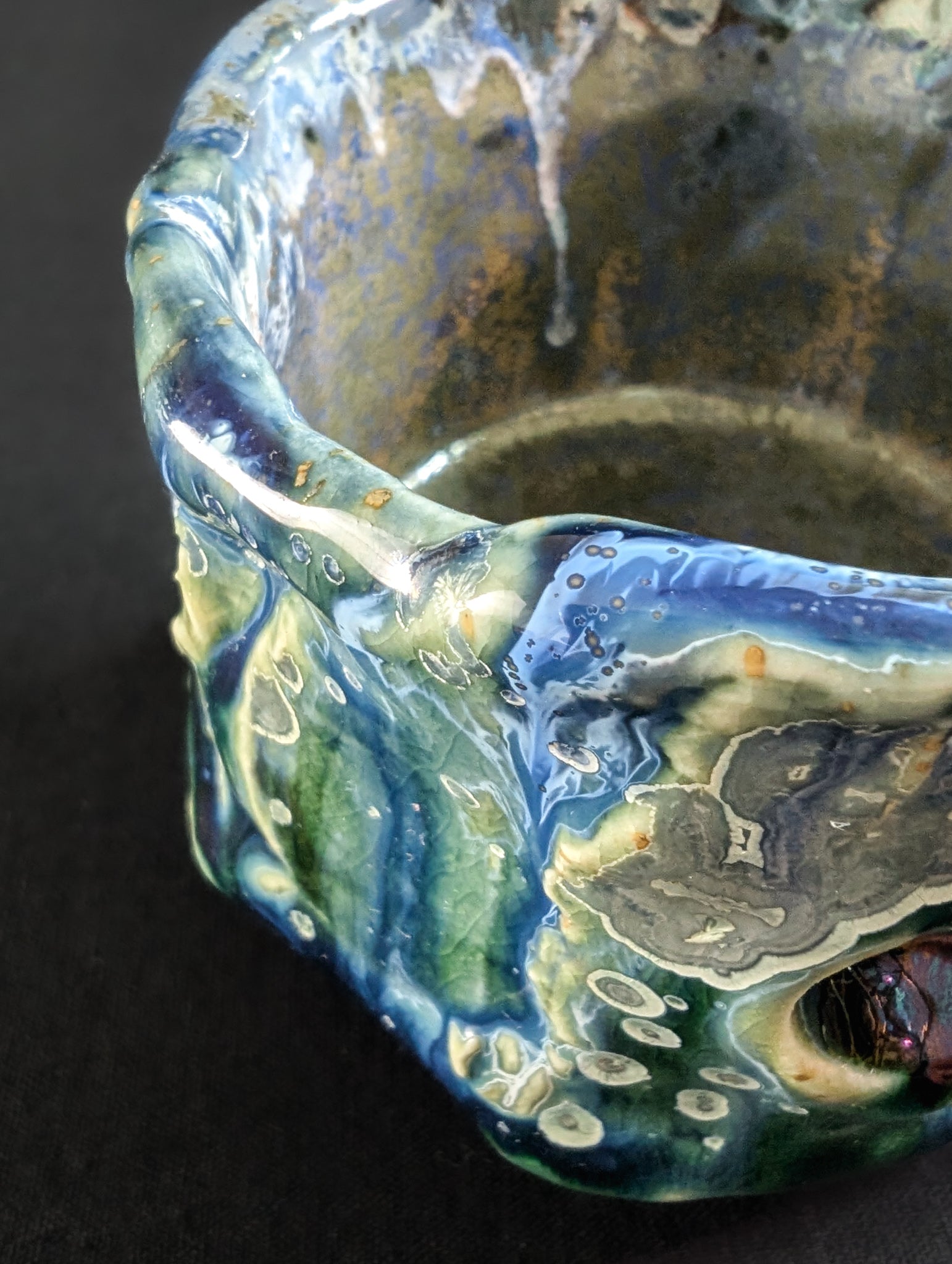 Close-up of the chawan's textured surface, featuring small yellow crystals with silver halos set in deep blue and green glaze.