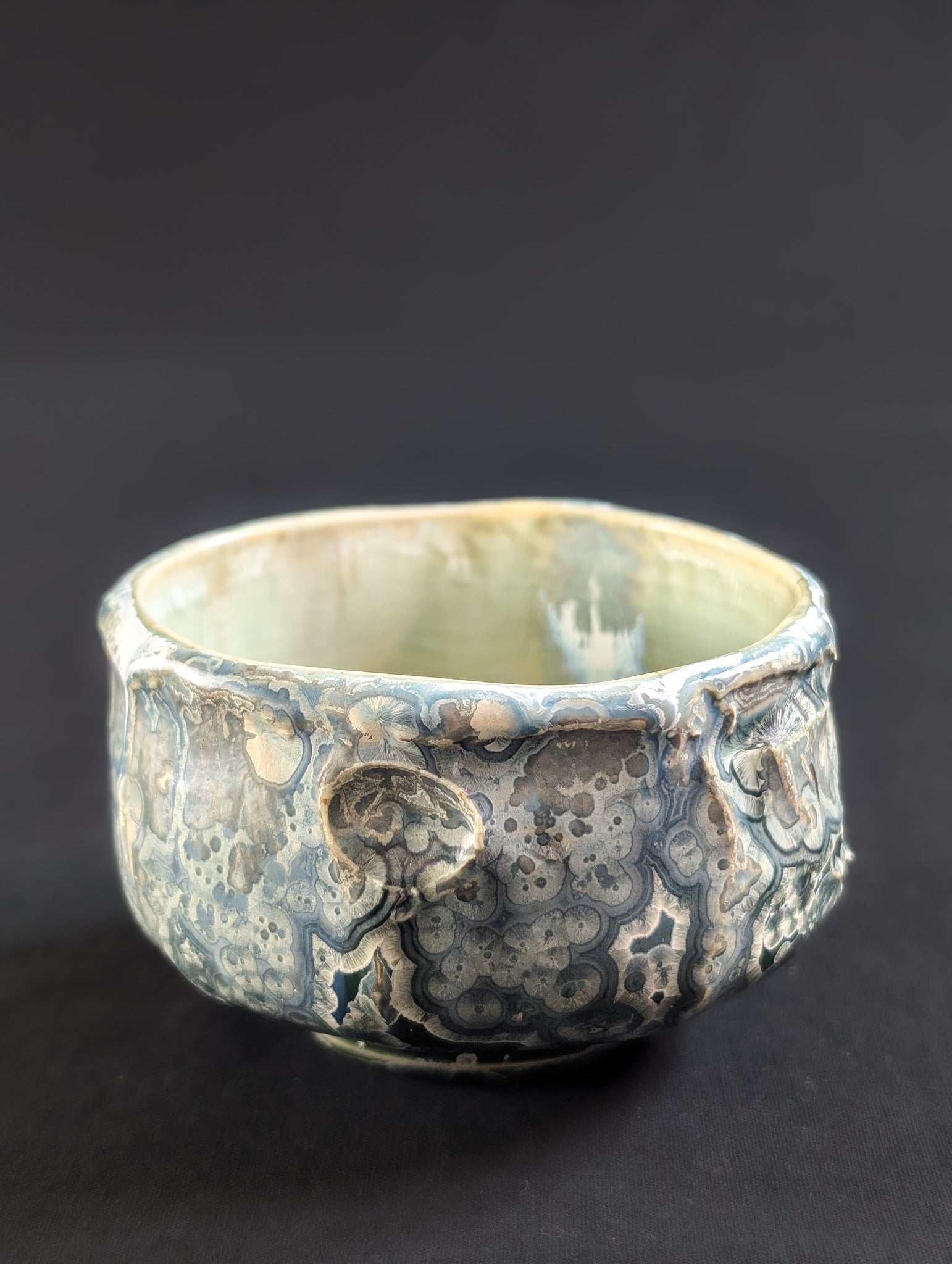 Angled profile of 'Tetsuya' tea bowl, showing subtle overcrystallization and pitted, meteor-like indentations.