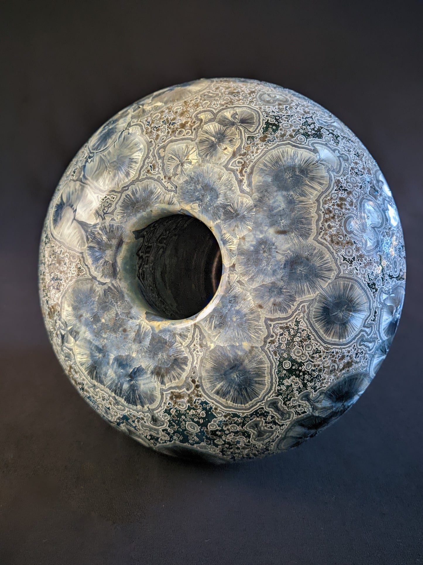 Top of porcelain vase titled "Milky Green Cosmos," featuring a green gradient background, large deep blue crystals with small silver ones.