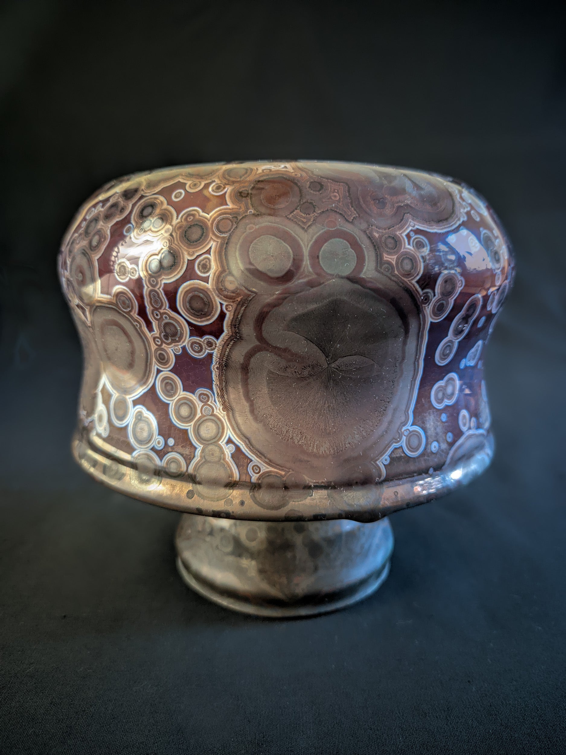 Crimson Halo reduction-fired mushroom vase with earthy brown crystals and a titanium outer ring, set against a gradient purple-to-red background. Short and wide shape, with a unique organic design.