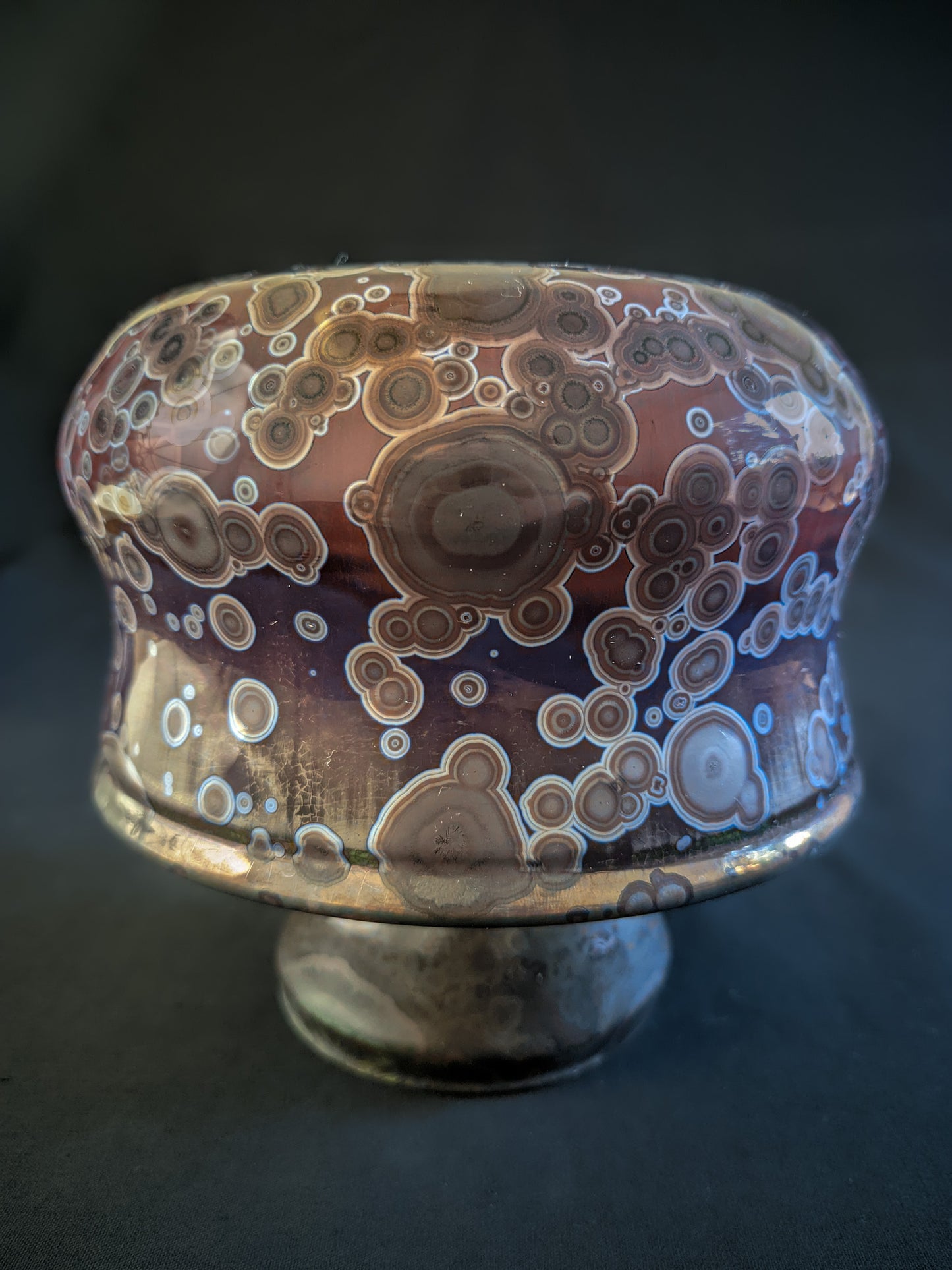 Crimson Halo reduction-fired mushroom vase with earthy brown crystals and a titanium outer ring, set against a gradient purple-to-red background. Short and wide shape, with a unique organic design.