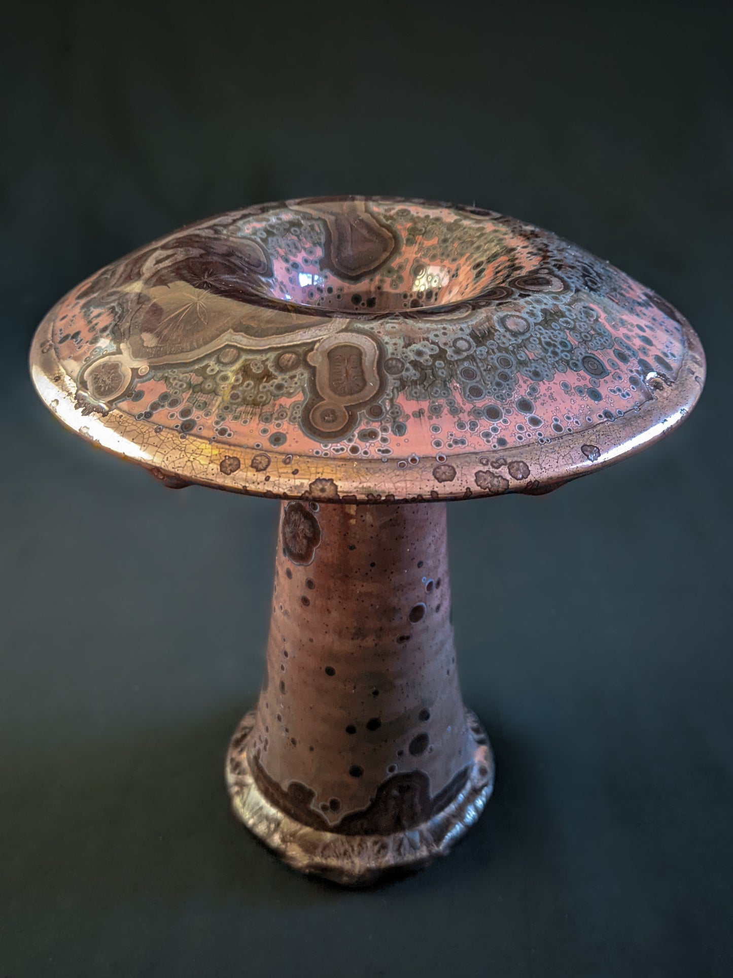 Red ceramic mushroom vase with golden crystals and a shiny rim, created using a reduction firing technique, with a tall, slender shape.