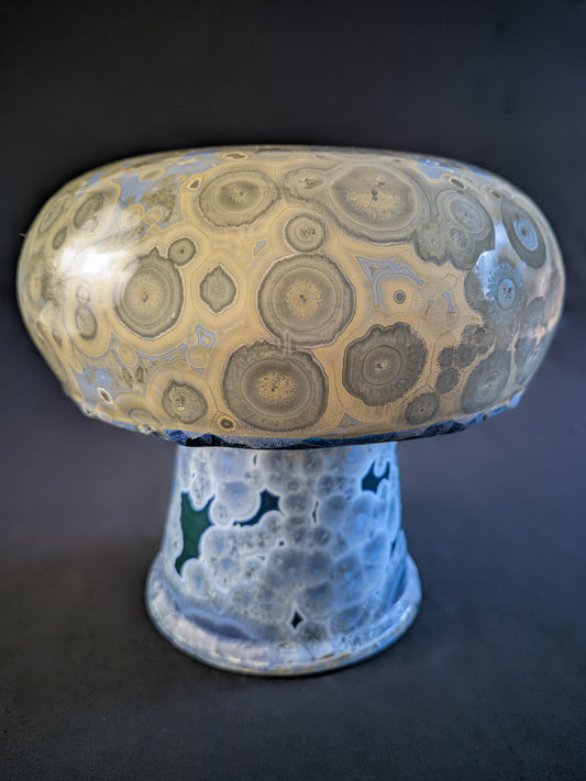 Chunky mushroom vase titled "Psychedelic Bloom" with a blue base featuring blue crystals and a bulbous yellow cap with beige crystals, showcasing intricate porcelain craftsmanship.