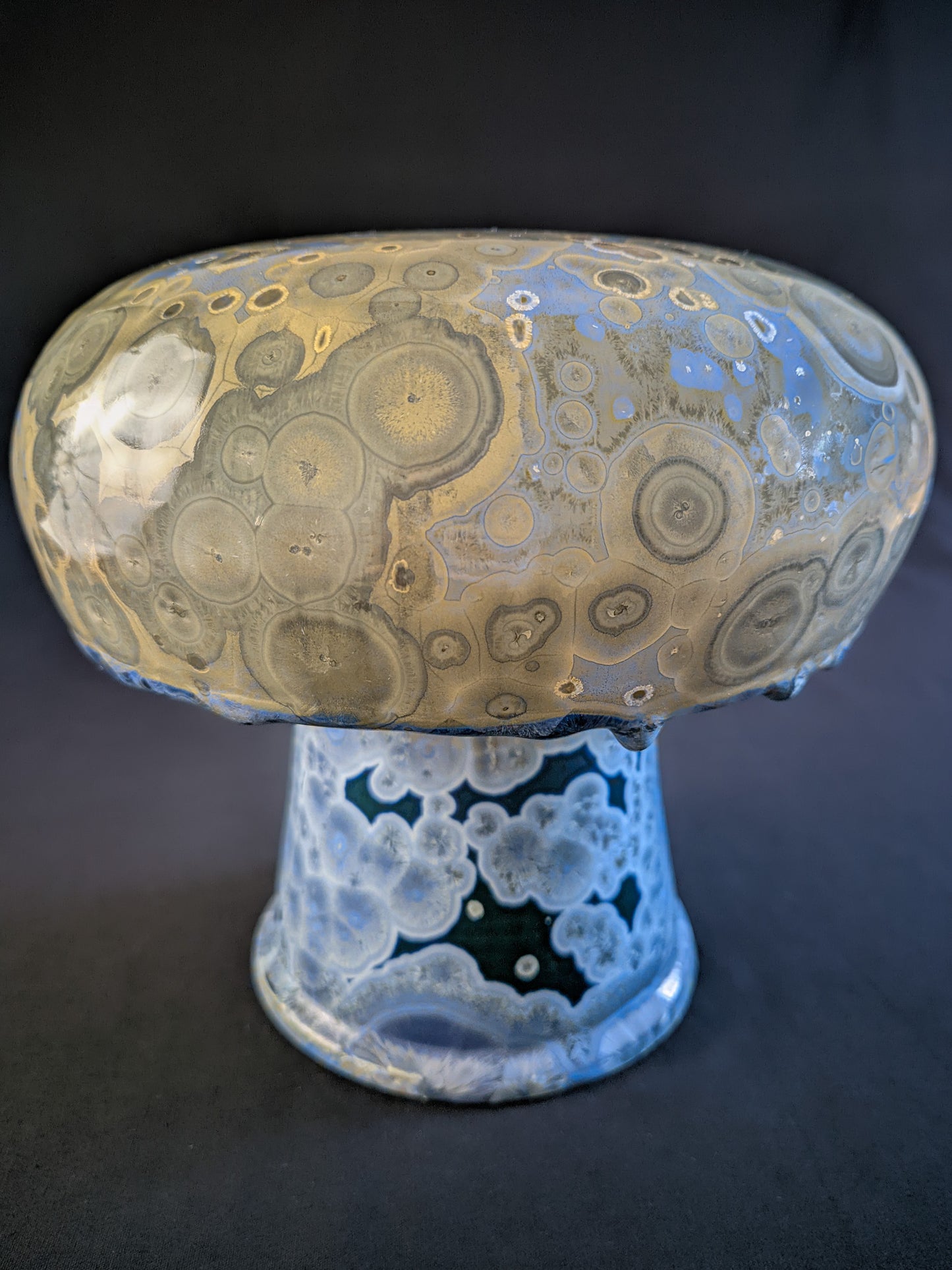 Chunky mushroom vase titled "Psychedelic Bloom" with a blue base featuring blue crystals and a bulbous yellow cap with beige crystals, showcasing intricate porcelain craftsmanship.