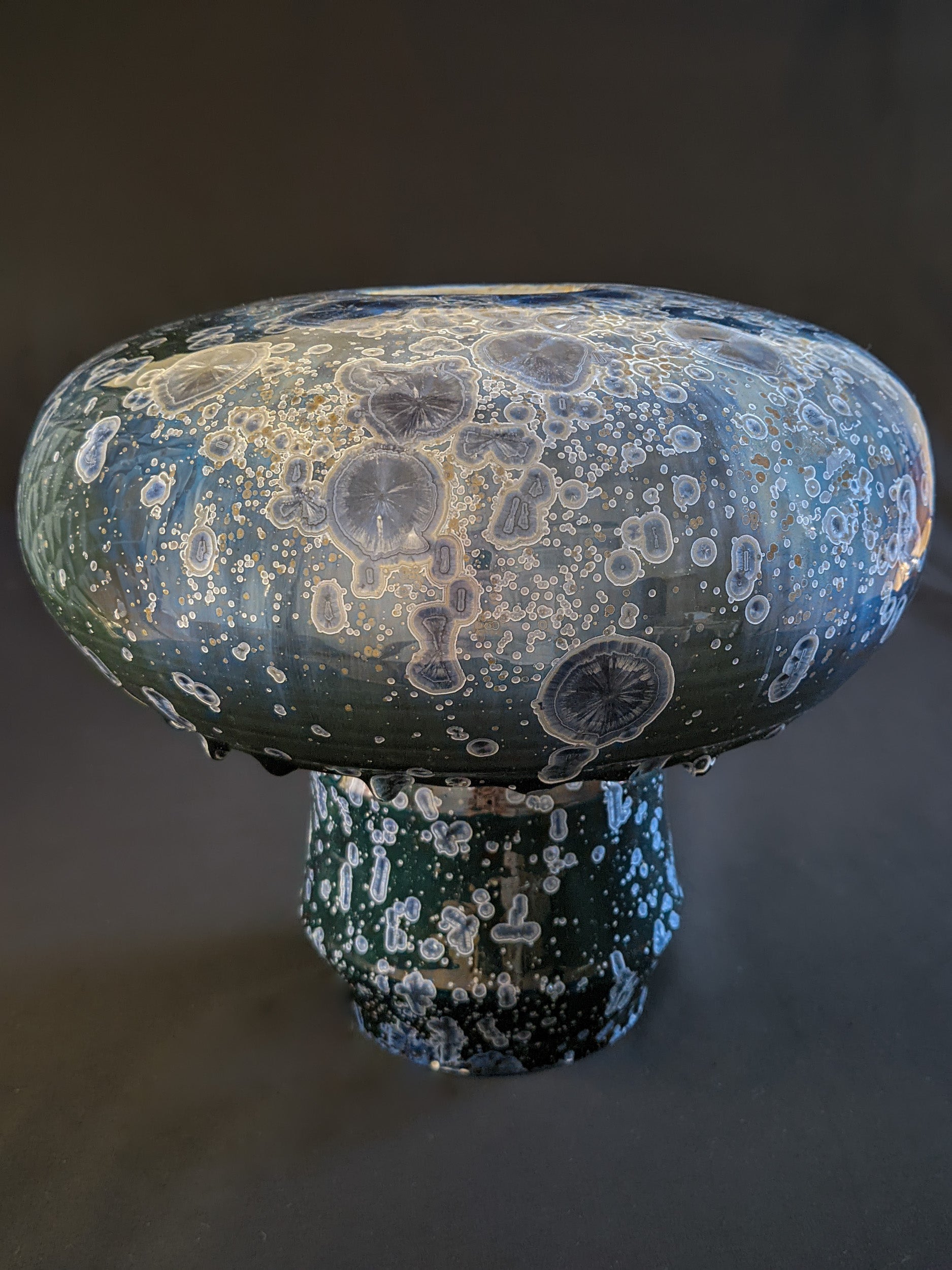 Large, round mushroom vase with a deep green to blue gradient background. The cap is smooth and round, while the chunky, faceted stem complements the deep blue crystals with silver rims. Magnificent crystalline structure with visible background and some larger crystals.