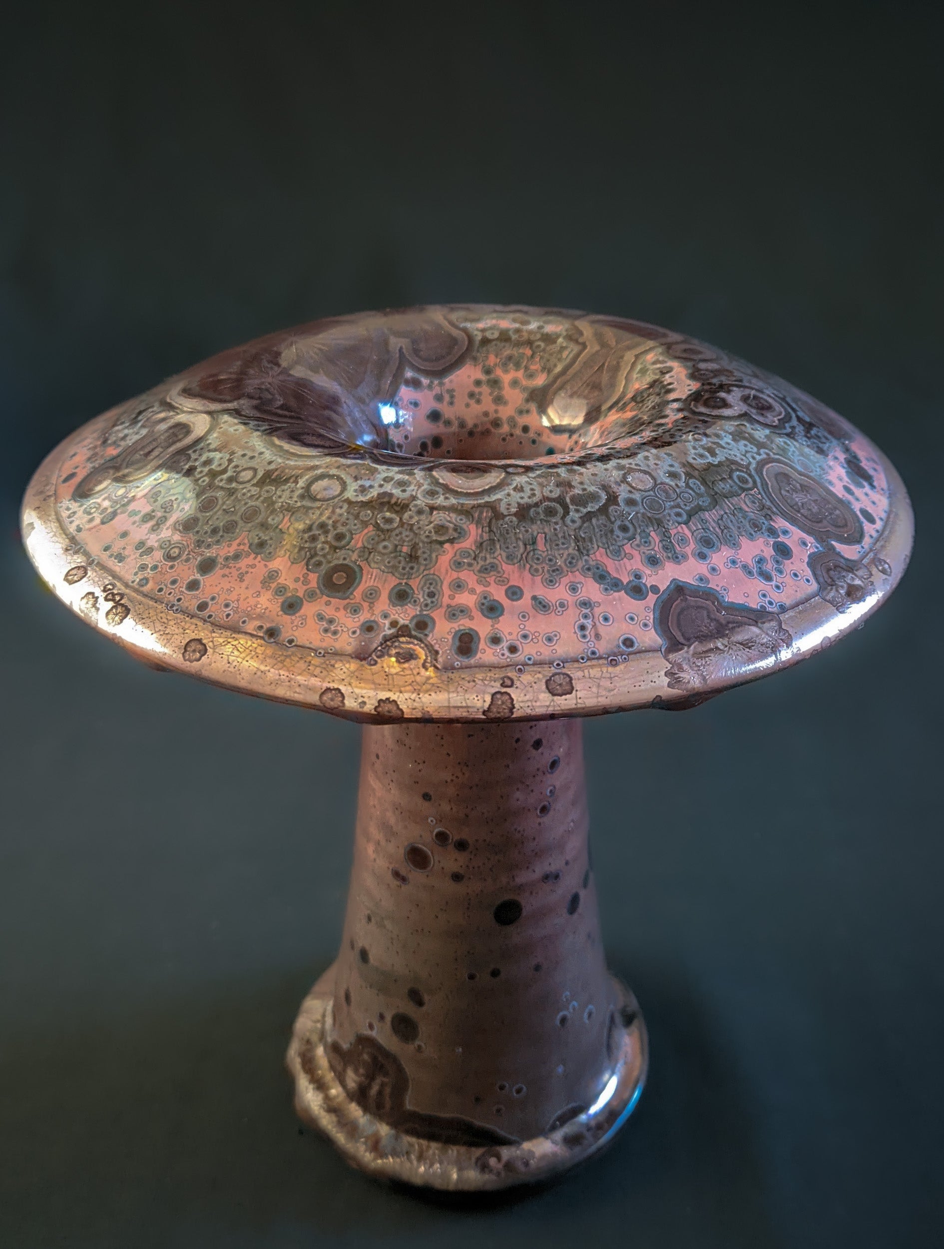 Red ceramic mushroom vase with golden crystals and a shiny rim, created using a reduction firing technique, with a tall, slender shape.