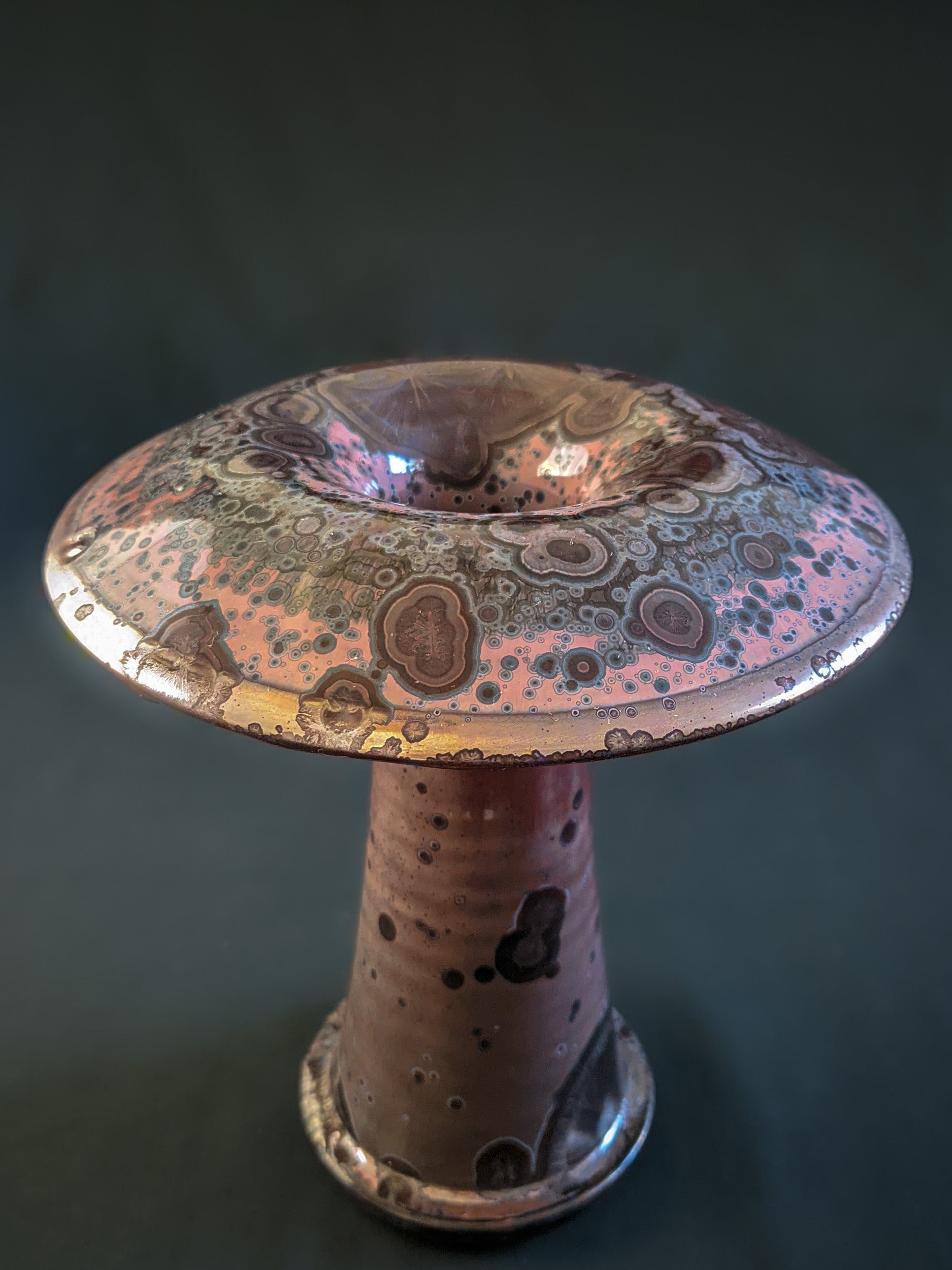 Red ceramic mushroom vase with golden crystals and a shiny rim, created using a reduction firing technique, with a tall, slender shape.