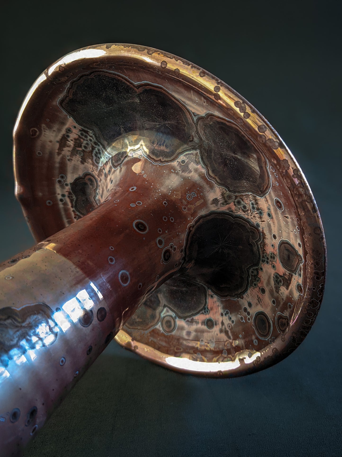 Red ceramic mushroom vase with golden crystals and a shiny rim, created using a reduction firing technique, with a tall, slender shape.